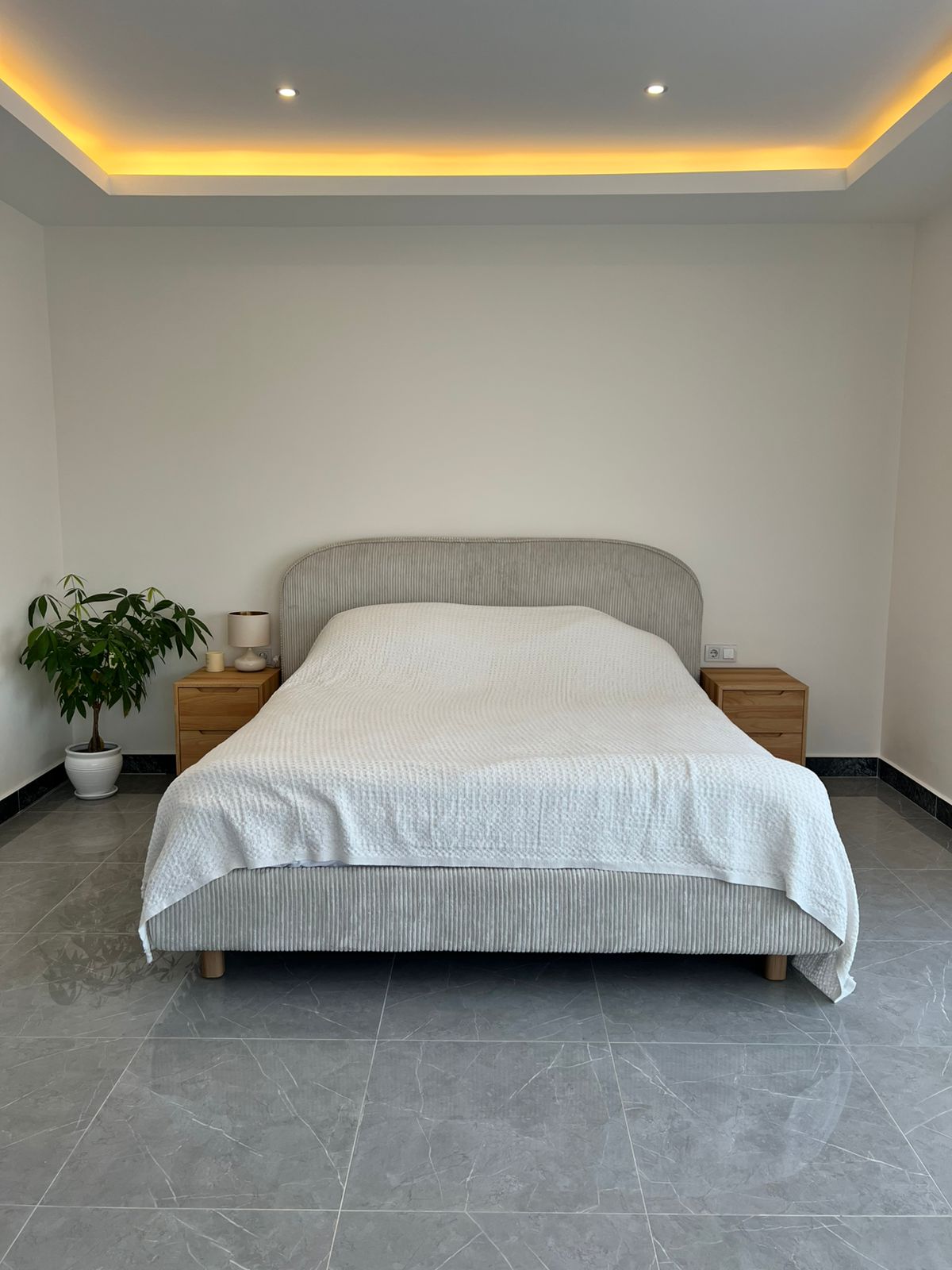 Tekstil başlıklı çift kişilik yataklı yatak odası, Oba’daki penthouse’un gizli tavan aydınlatmasını gösteriyor
