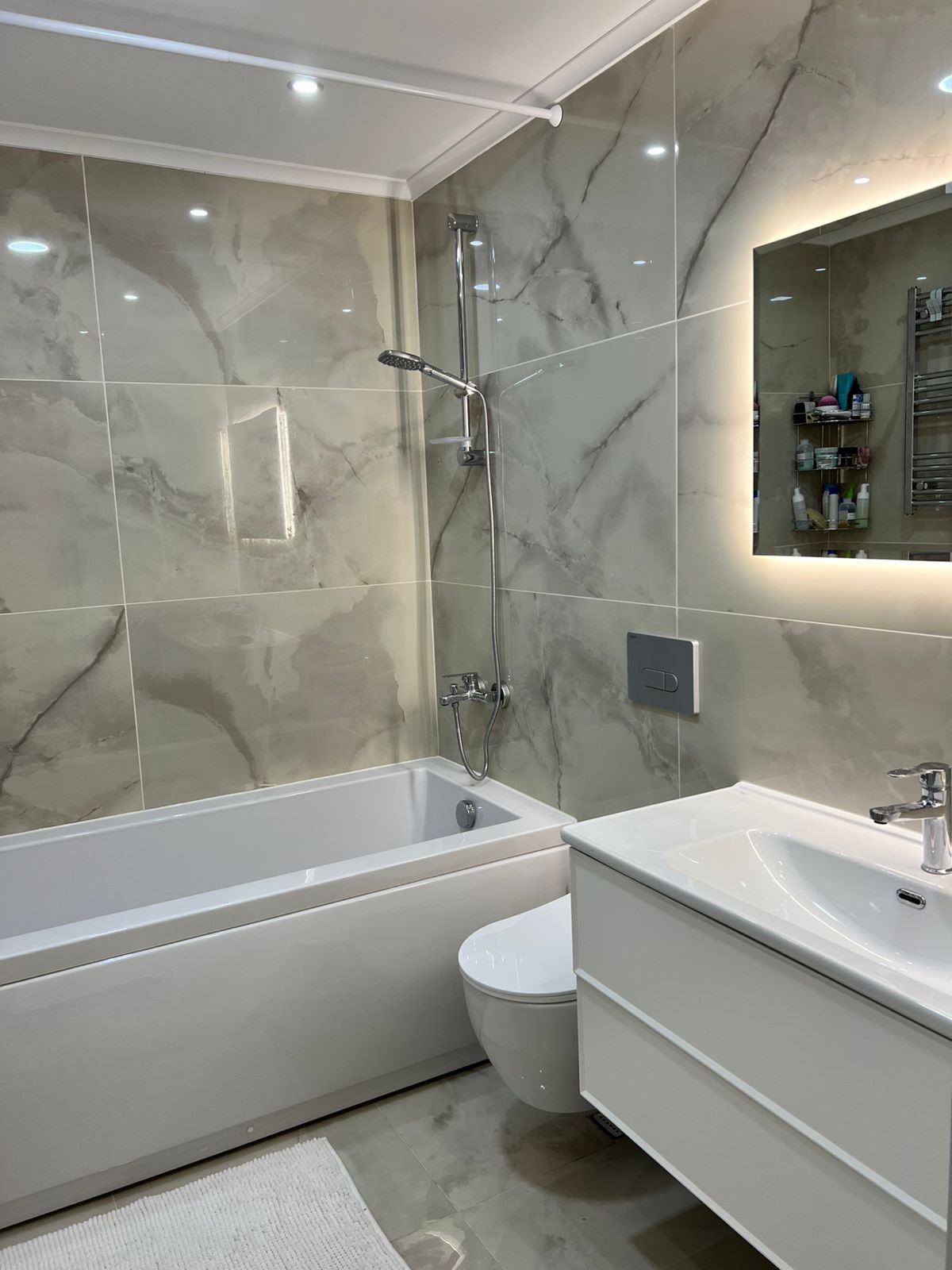 Beyaz küvetli, lavabolu ve ışıklı aynalı banyo Oba’daki 2+1 rezidansın içinde bulunuyor