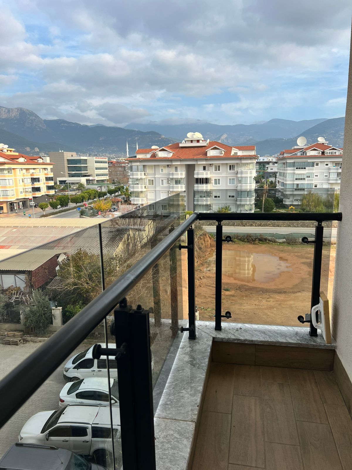 Cam korkuluklu ve metal tırabzanlı balkon, Türkiye’de satılık penthouse’un dağ sırtı manzarasını açıyor
