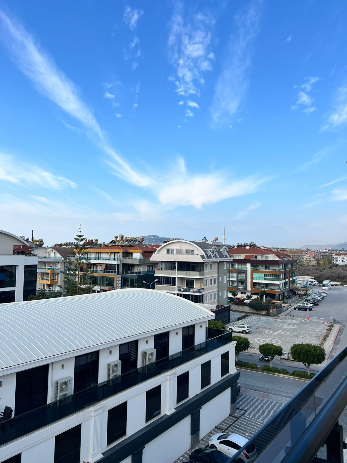 Cam korkuluklu penthouse balkonu Oba’da Türkiye’deki şehir sokağı ve park edilmiş araçlara bakıyor