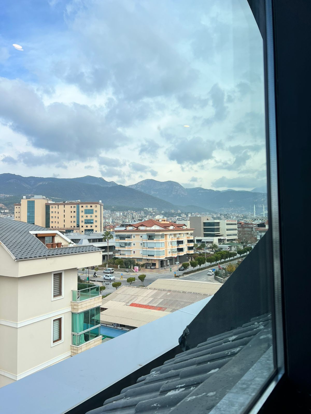 Panoramik pencereden şehir ve dağ sırtı görünen satılık penthouse’ta araçlı sokak izleniyor