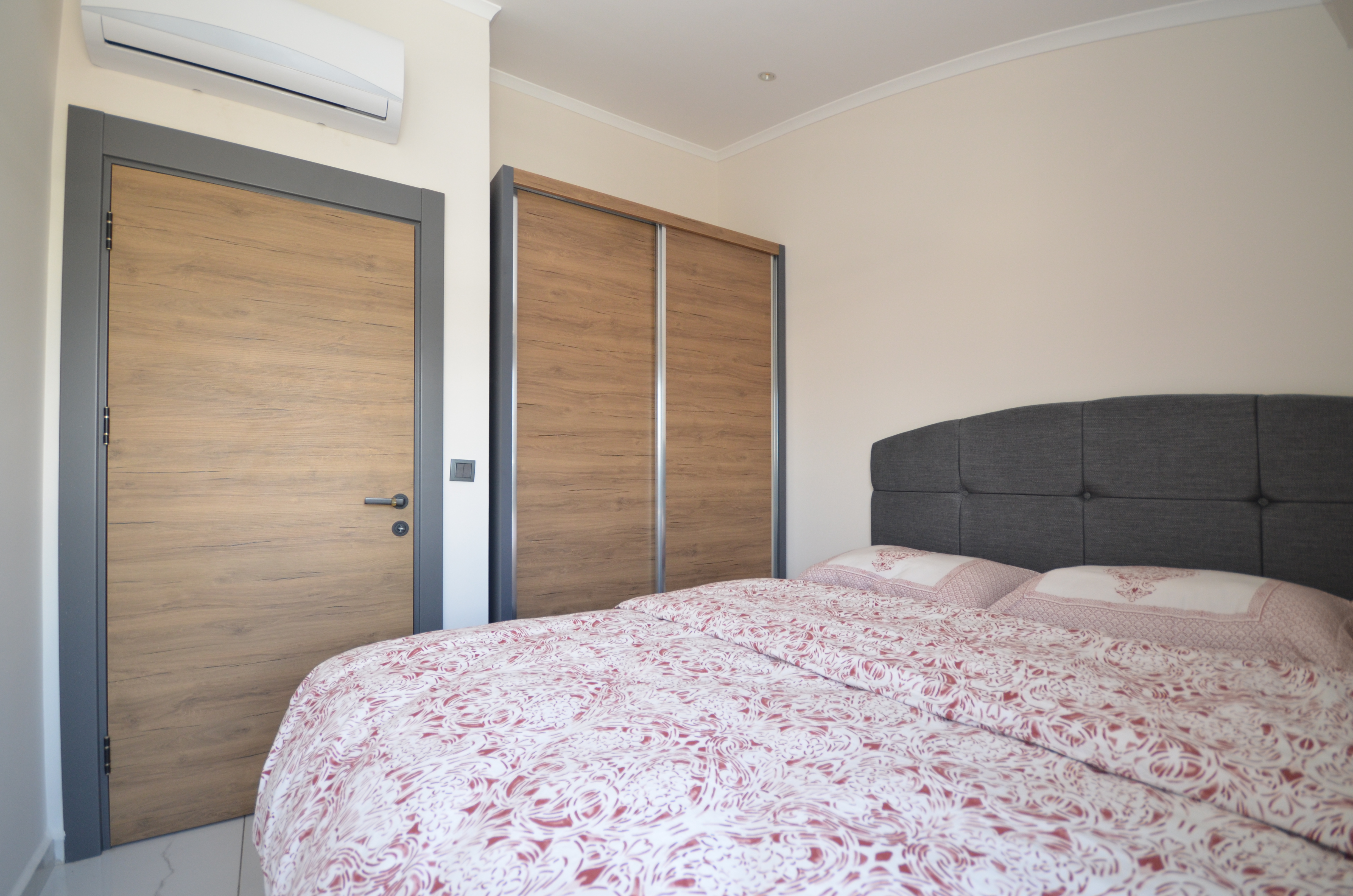 Спальня с красно-белым покрывалом, шкафом-купе и кондиционером в резиденции