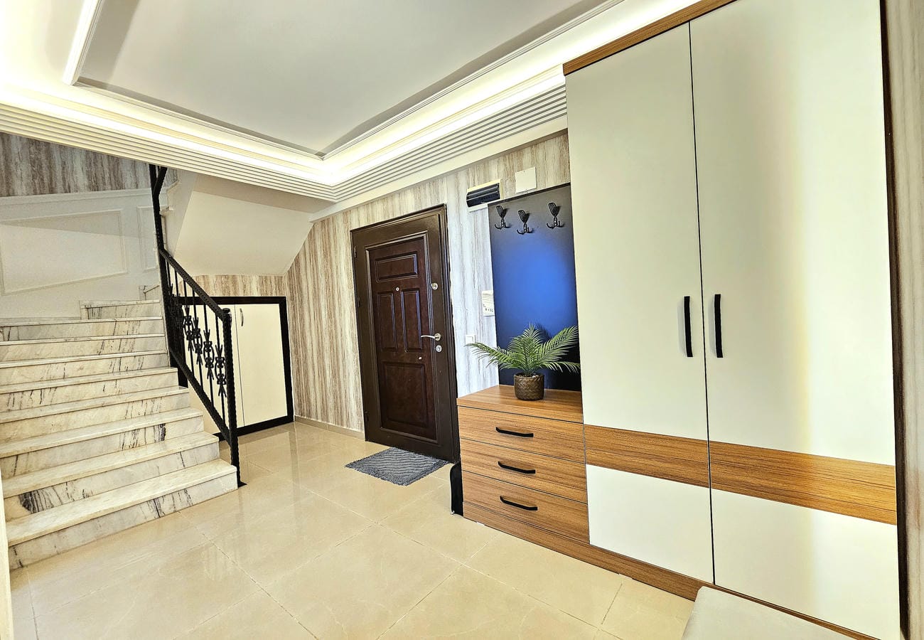 Mermer merdivenli antre Oba’daki penthouse dairesinin beyaz gömme dolabıyla
