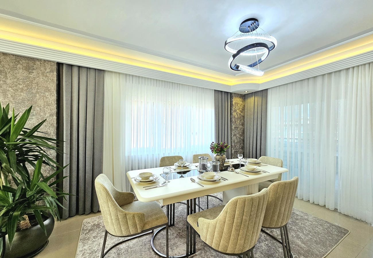 Altı sandalyeli yemek odası Oba’daki penthouse dairesinde panoramik köşe pencerelerle