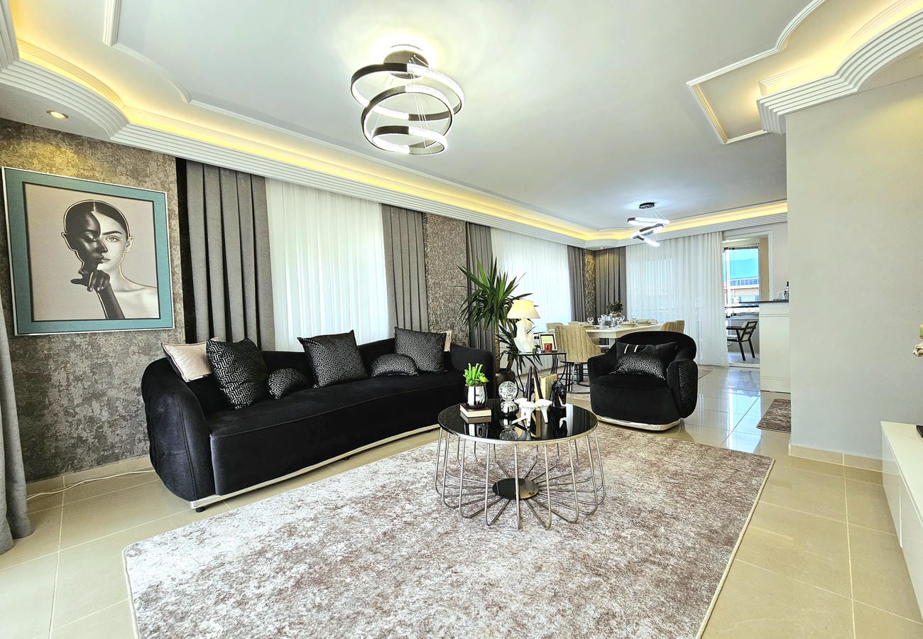 Siyah köşe koltuklu salon Türkiye’de rezidans dairesinin panoramik pencereleriyle