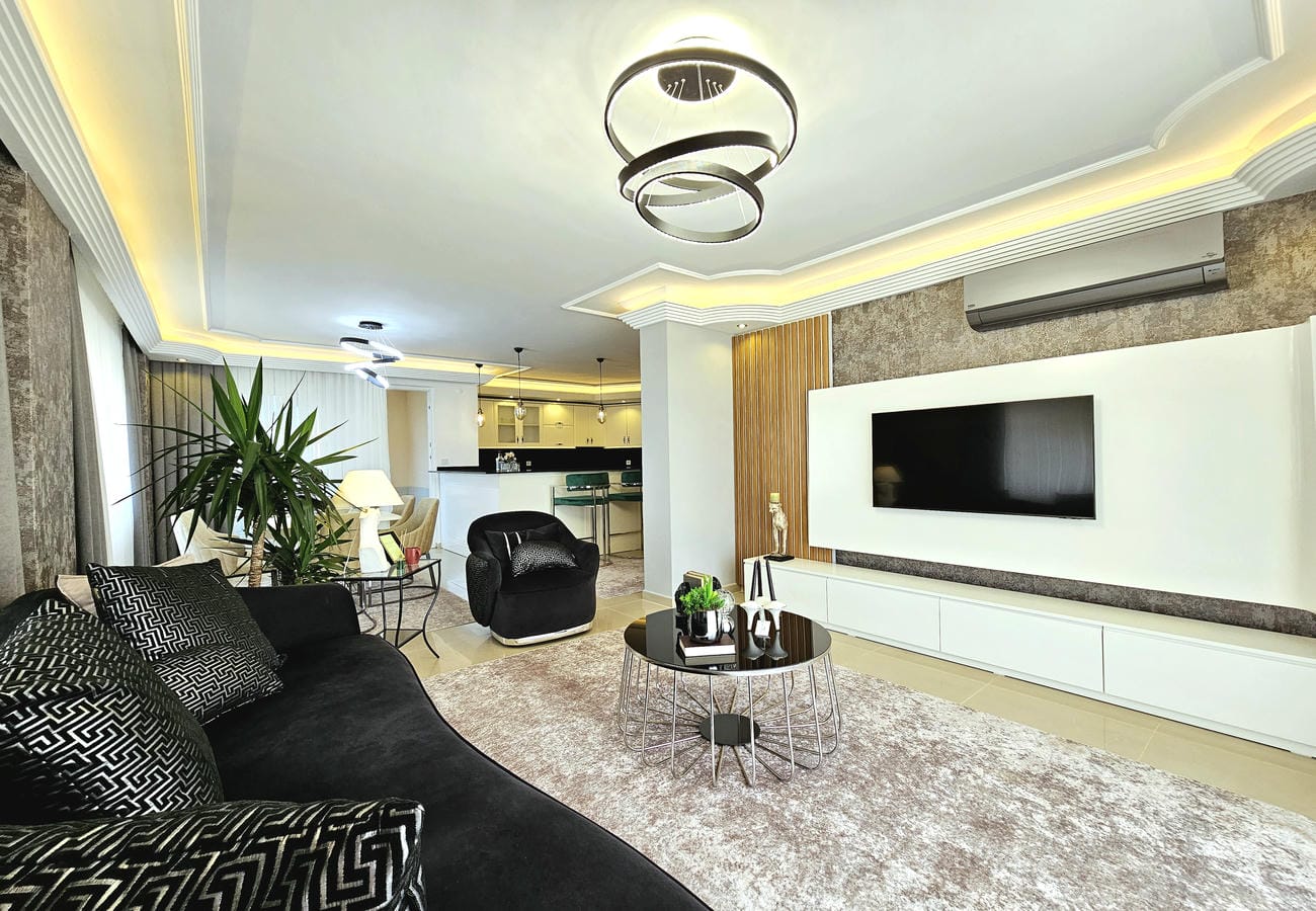 Televizyonlu salon Oba’daki penthouse dairesinde arkadaki mutfak alanıyla