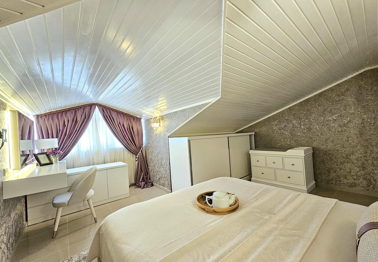 Krem yataklı yatak odası Oba’daki penthouse dairesinde makyaj masası ve mor perdelerle