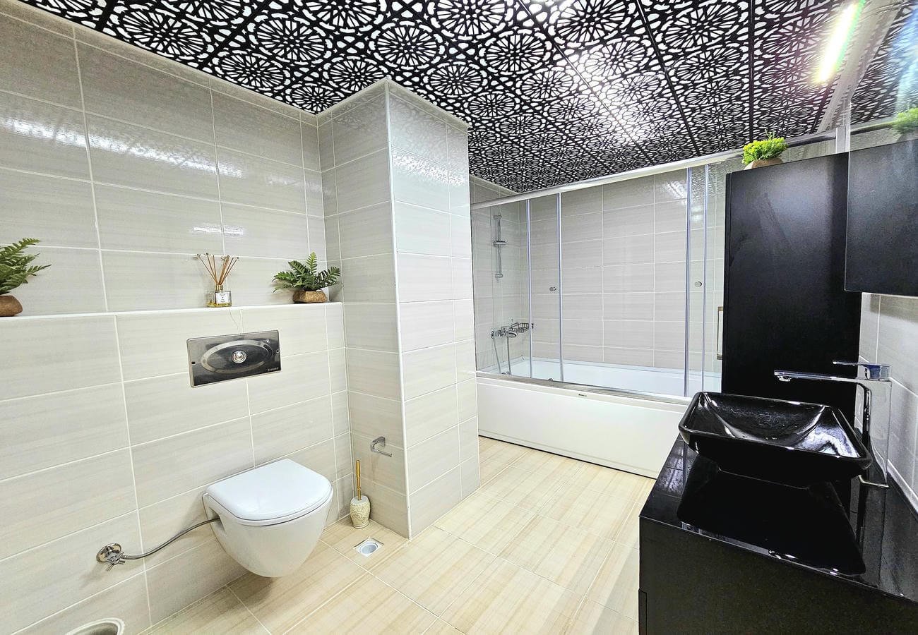 Hidromasajlı küvetli banyo penthouse dairesinde cam duş bölmesi ve siyah lavabo ile