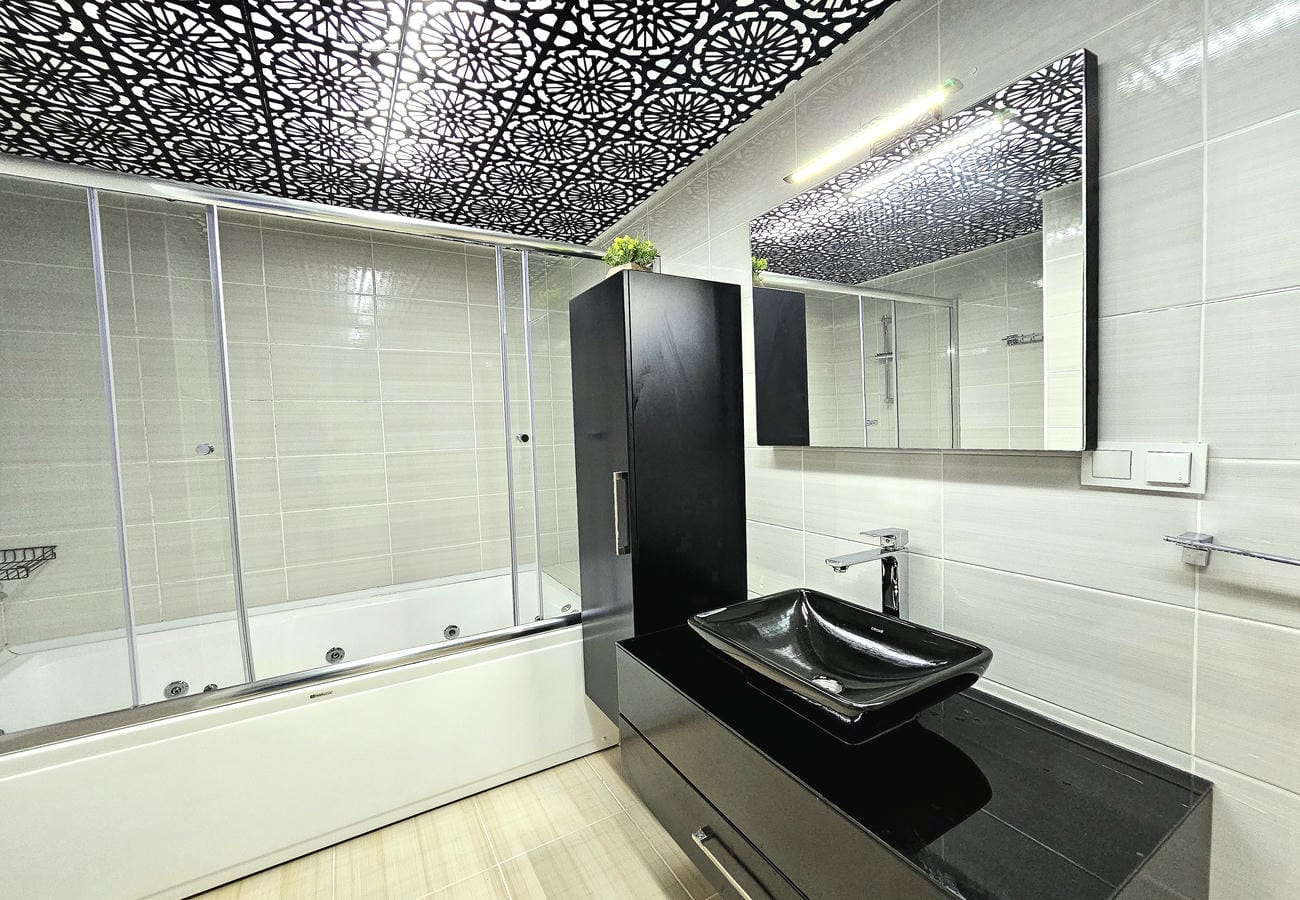 Hidromasajlı küvetli banyo Oba’daki rezidans dairesinde siyah lavabo ve aynayla