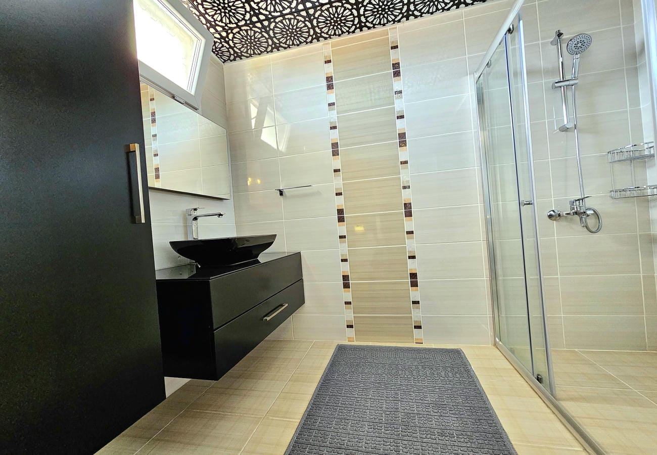 Cam duş kabinli banyo siyah lavabo ve küçük pencereyle
