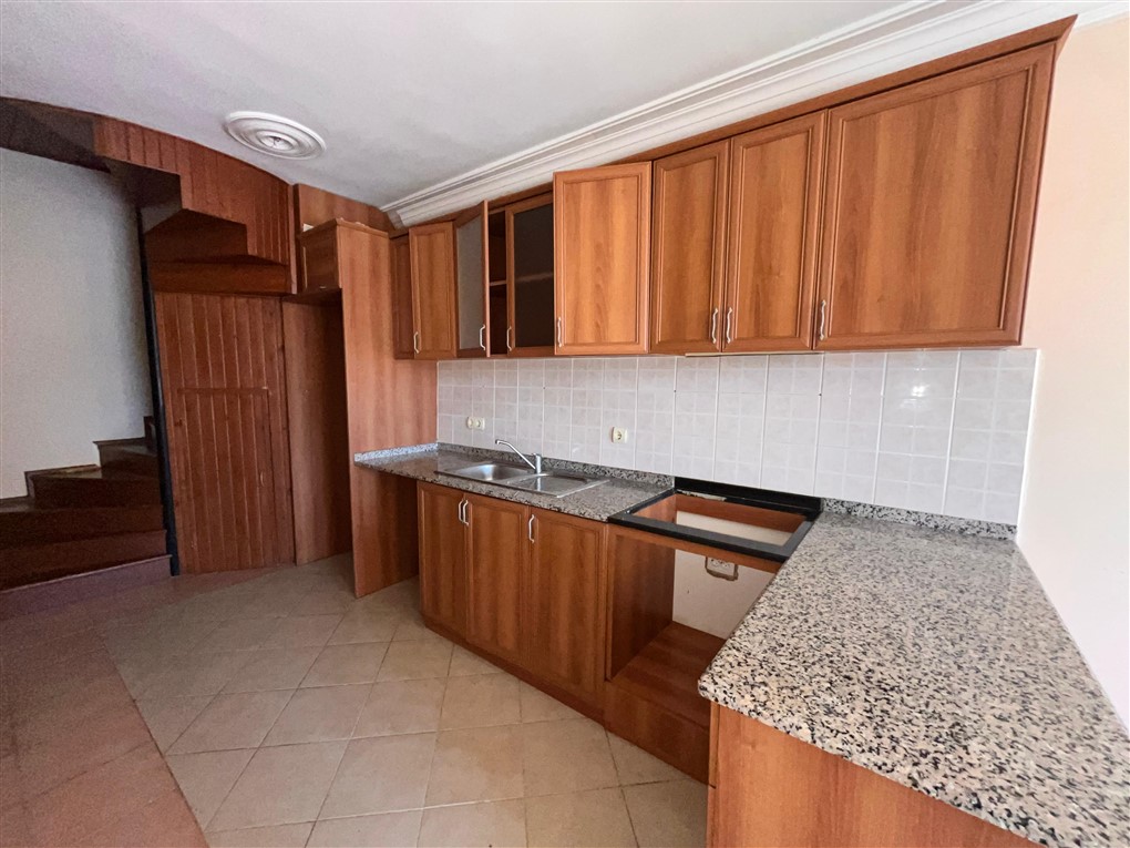 Ahşap köşe mutfak dolabı ve granit tezgâhlı mutfak beyaz fayans backsplash ile
