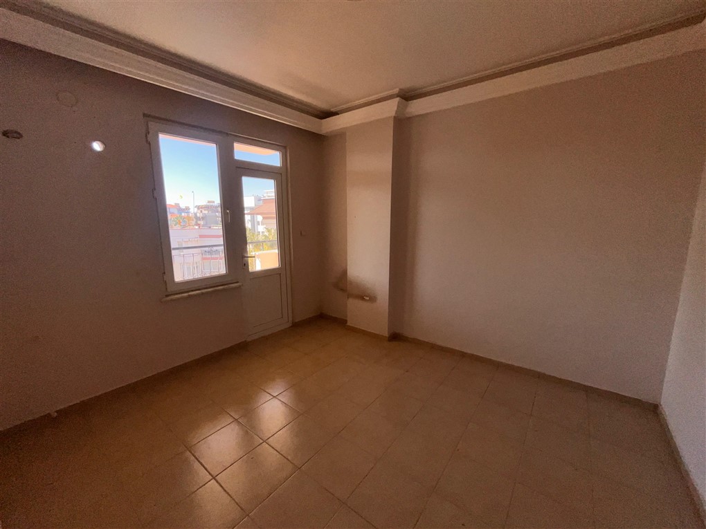 Balkon kapılı boş oda ve dışarıdaki şehir binaları Oba’daki rezidansta