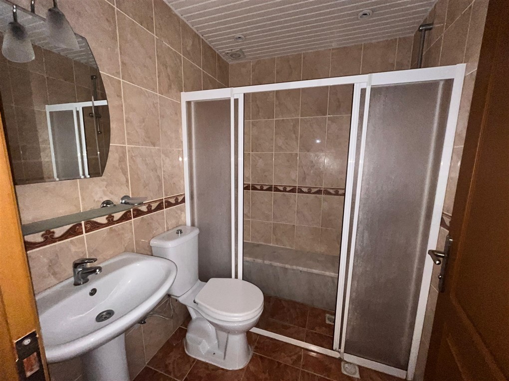 Beyaz profilli duş kabinli banyo ve çıtalı tavan üst kattaki rezidansta