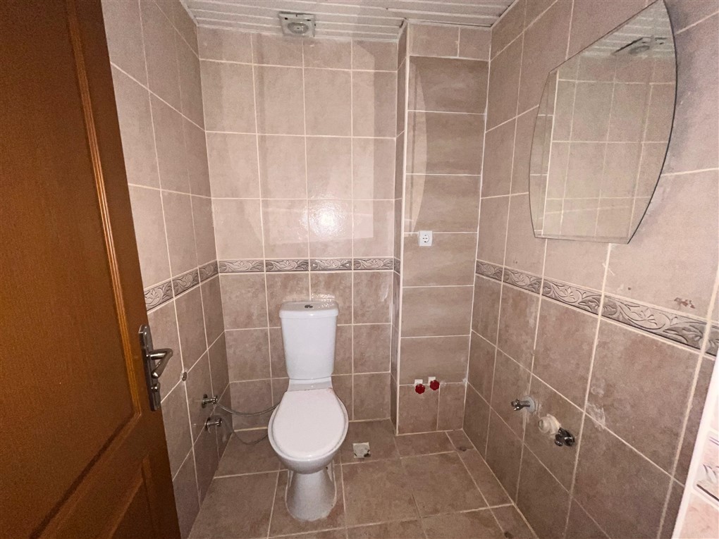Beyaz klozetli ve aynalı banyo Oba’daki konutta