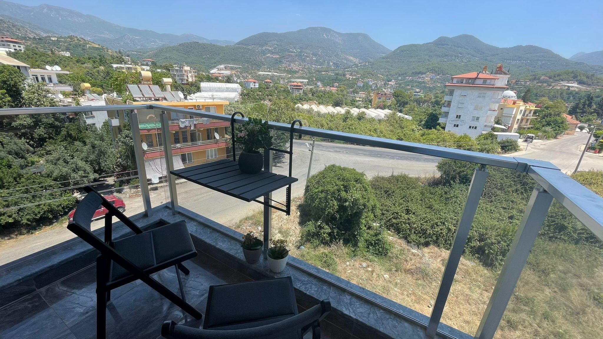 Terasta cam korkuluk, asılı sandalye ve panoramik dağ manzarası Oba'daki penthouse, Türkiye'de
