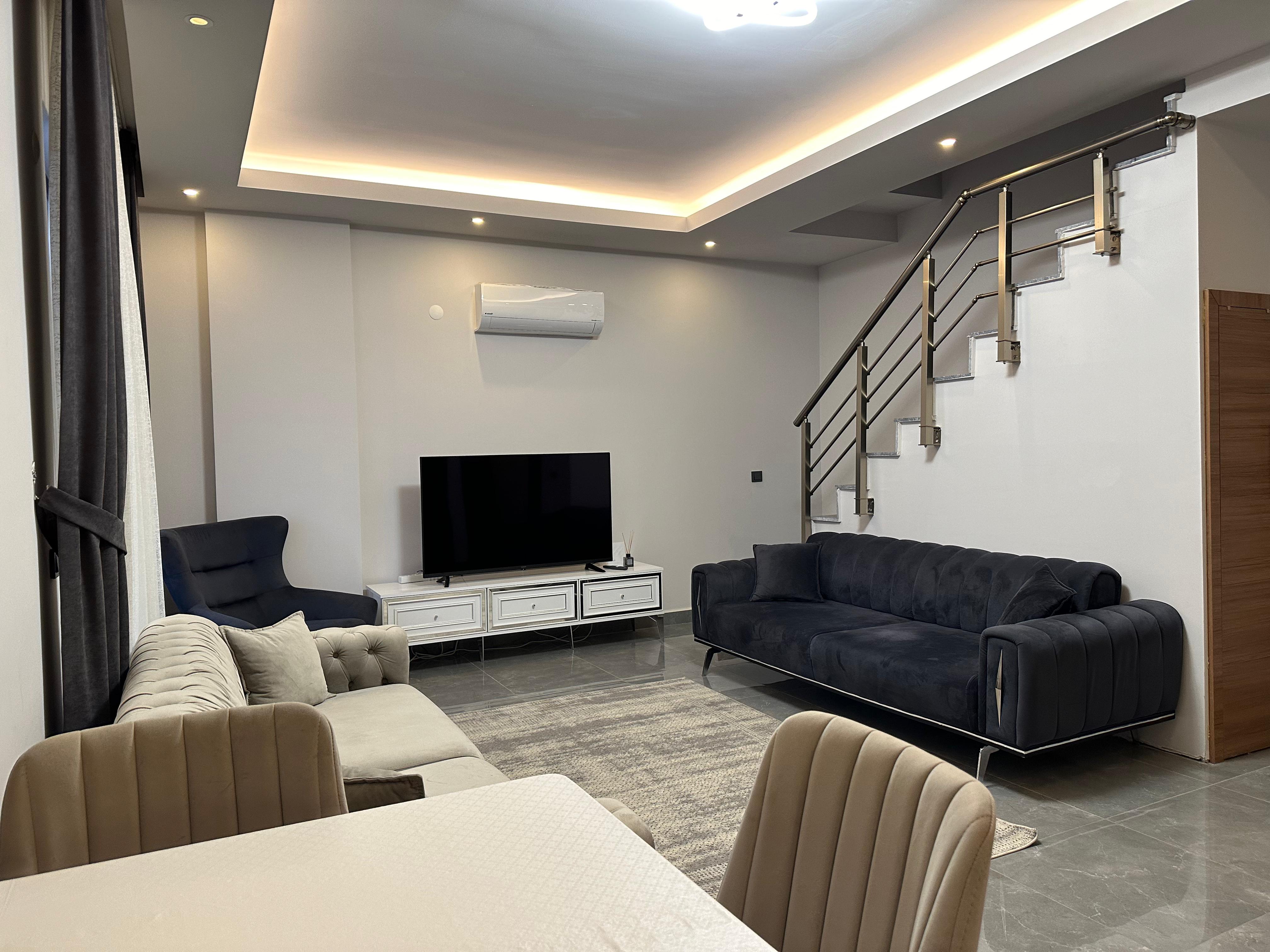 Kitchen-living room with two sofas, a TV and a staircase in a residence for sale