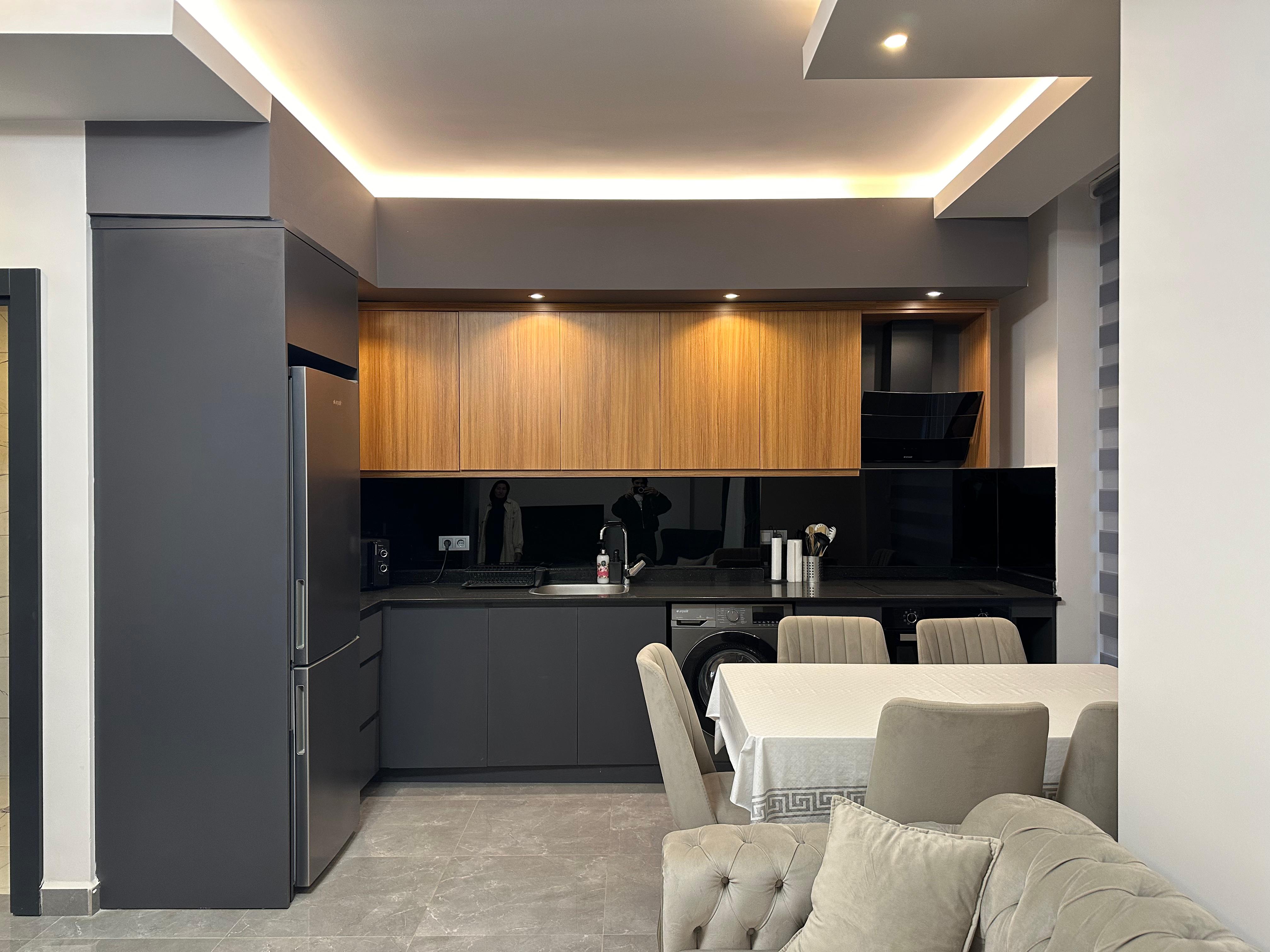 Black kitchen cabinetry with an integrated fridge and dining area in a residence