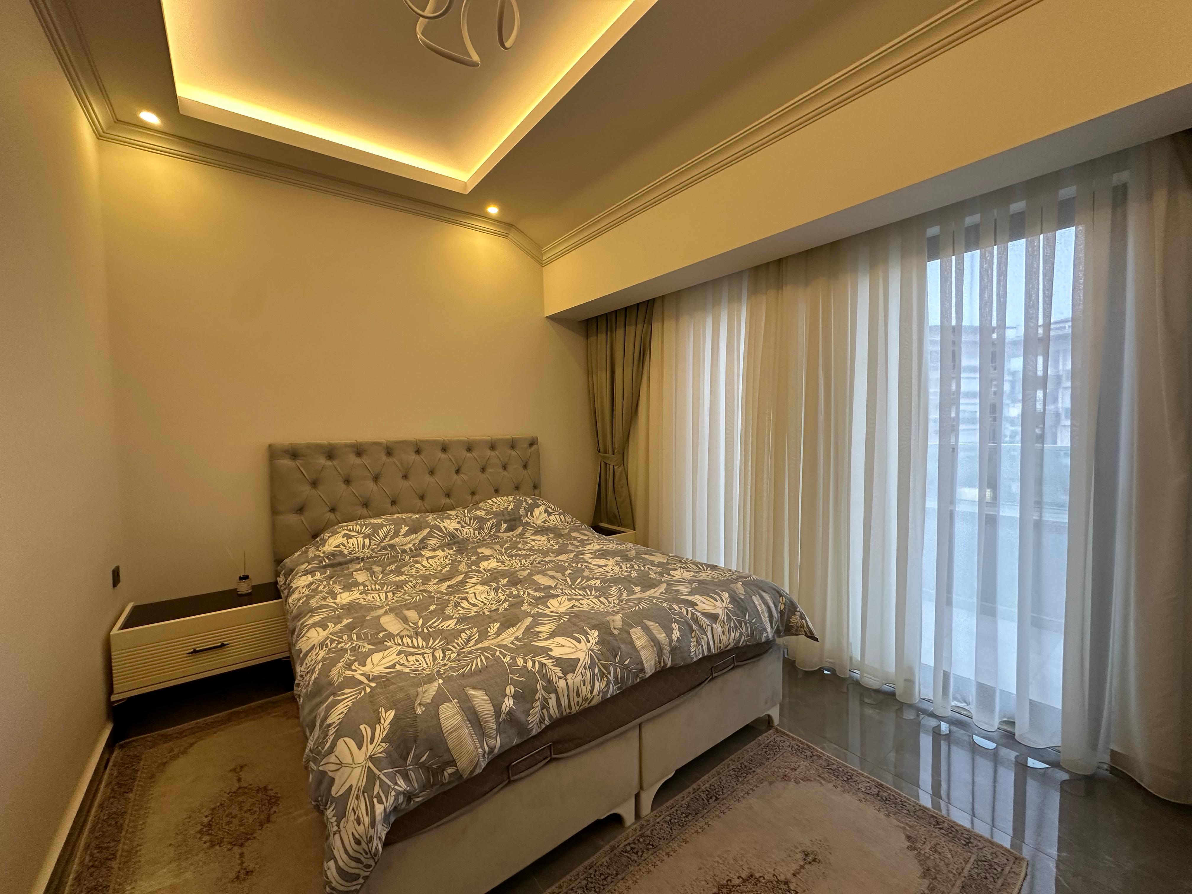 Bedroom with a double bed, botanical-patterned coverlet and panoramic window in Oba