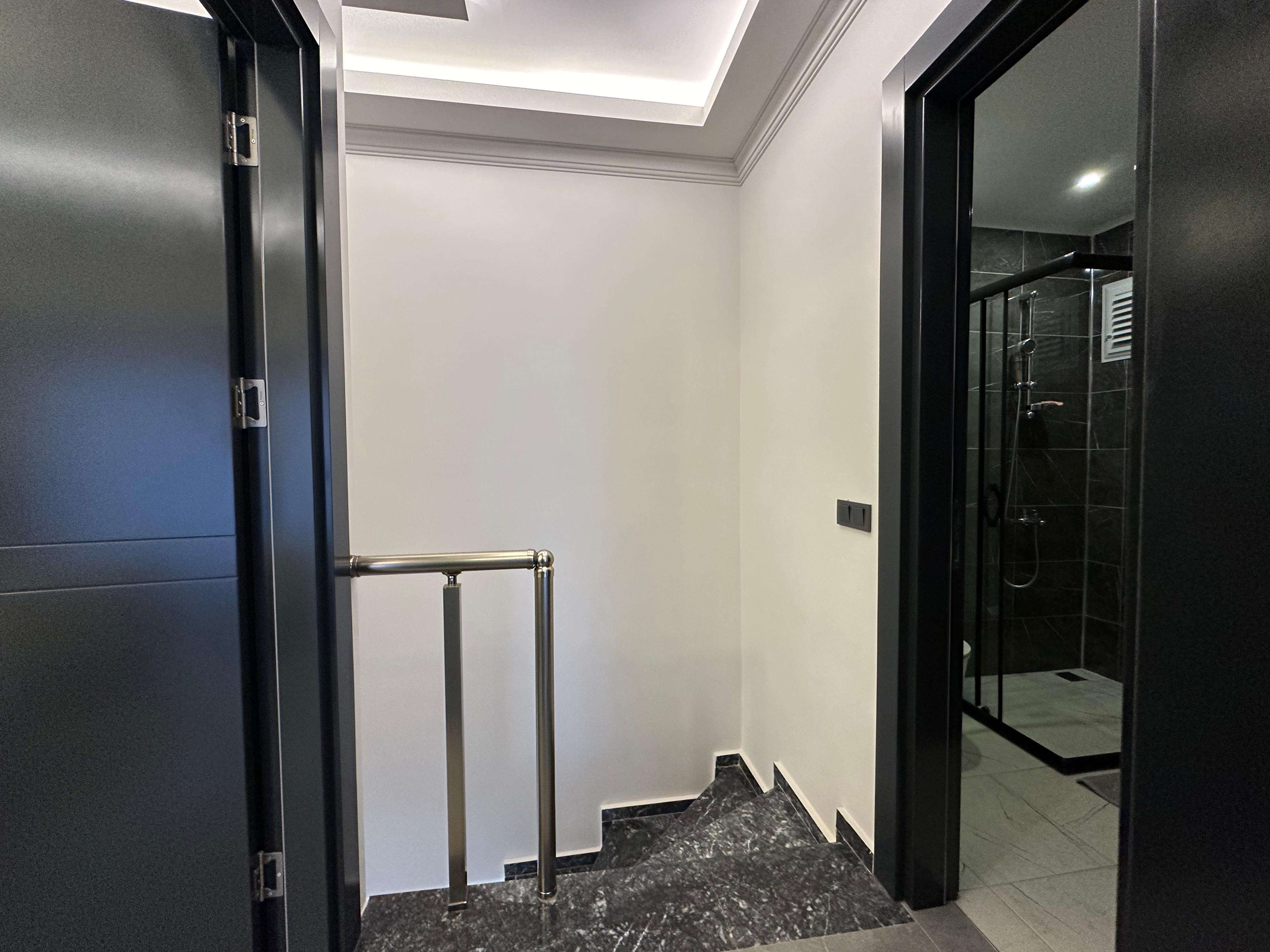 Stairwell with a metal handrail, black doors and ceiling lighting in Oba