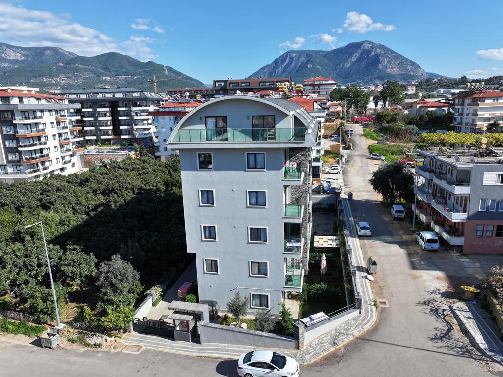 High-rise residential facade with a curved top floor and glass balconies in Oba, Alanya, Turkey