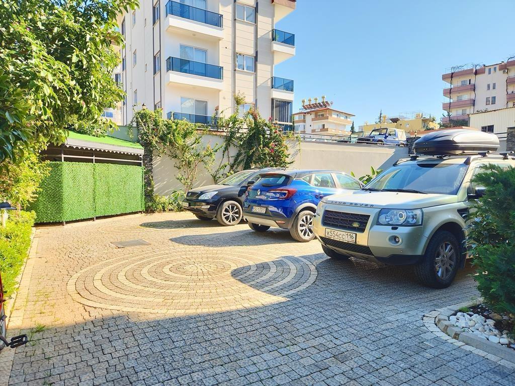 Open parking area with three cars and a hedge for penthouse residents