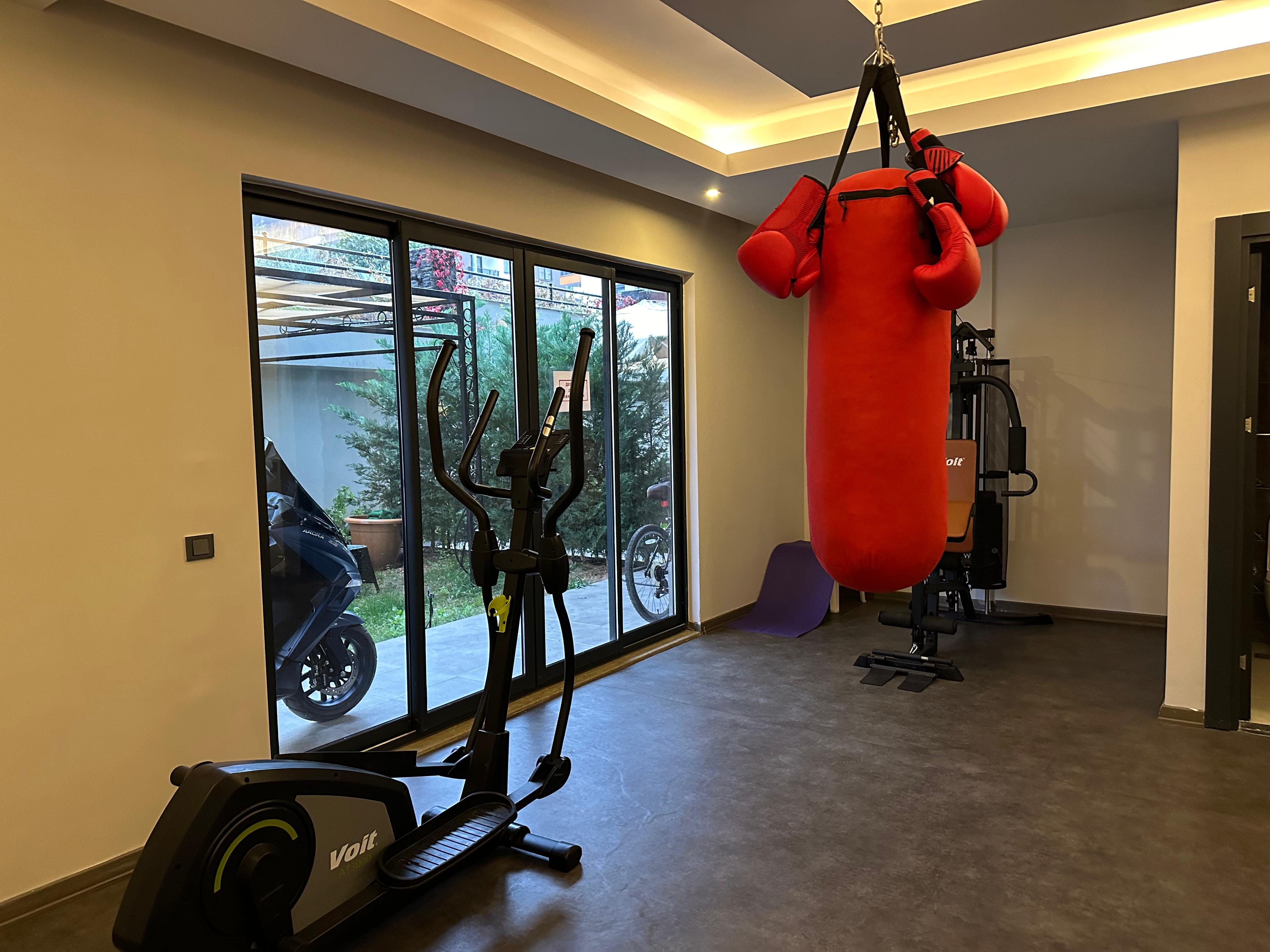 Gym with a punching bag and elliptical trainer for residents of penthouses in Oba