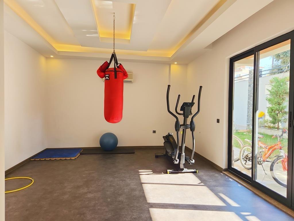 A gym with a red punching bag, elliptical trainer and blue exercise ball for duplex residents