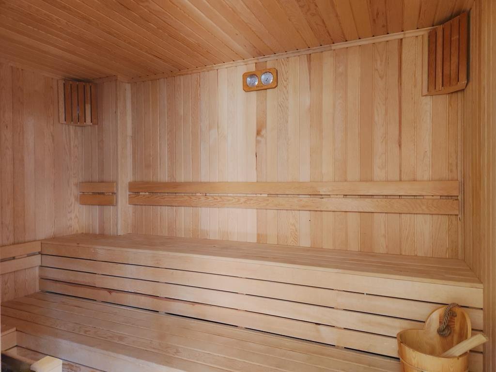 Wood-paneled sauna with tiered benches and a wall thermometer for penthouse residents