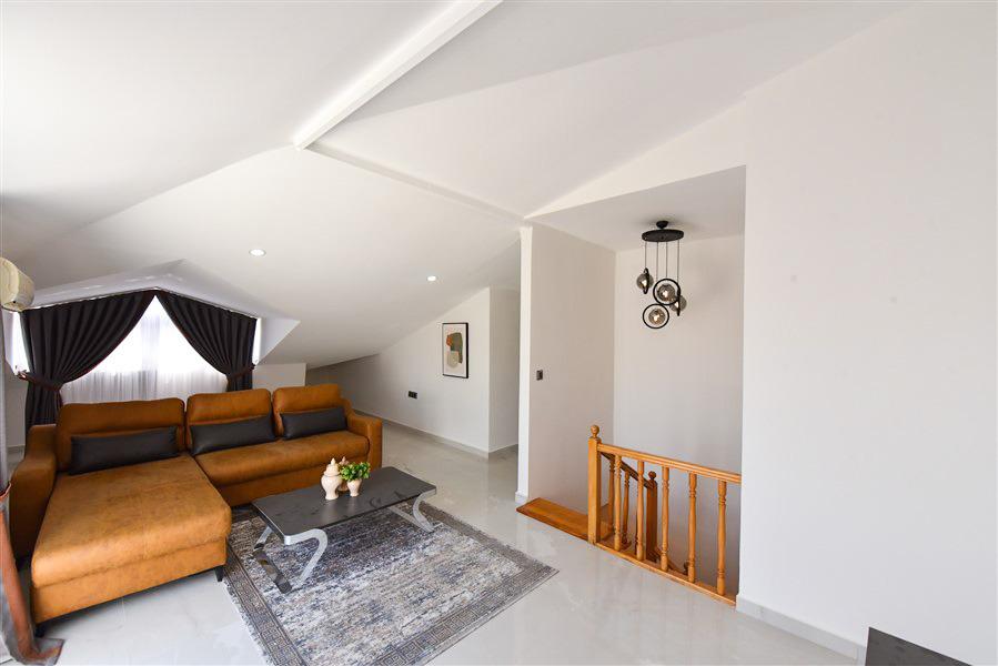 Kahverengi köşe kanepeli salon ve ahşap merdiven Türkiye’deki penthouse dairenin iç mekânında