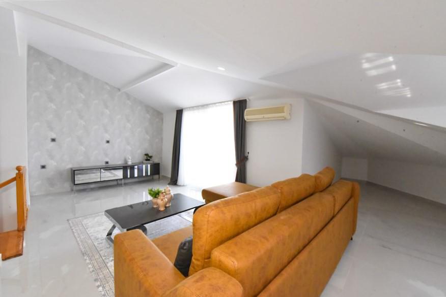 Kahverengi köşe kanepeli salon eğimli tavanıyla Oba’da satılık penthouse içinde yer alıyor
