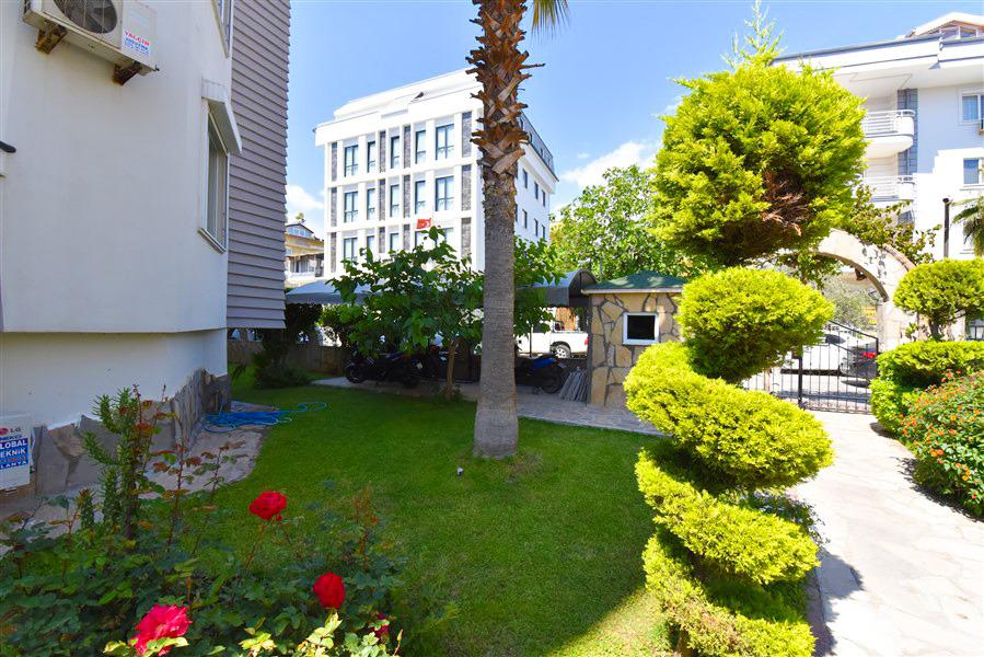 Güllü çim alan ve ortadaki palmiyeyle Türkiye’de satılık penthouse dairelerin bulunduğu rezidans
