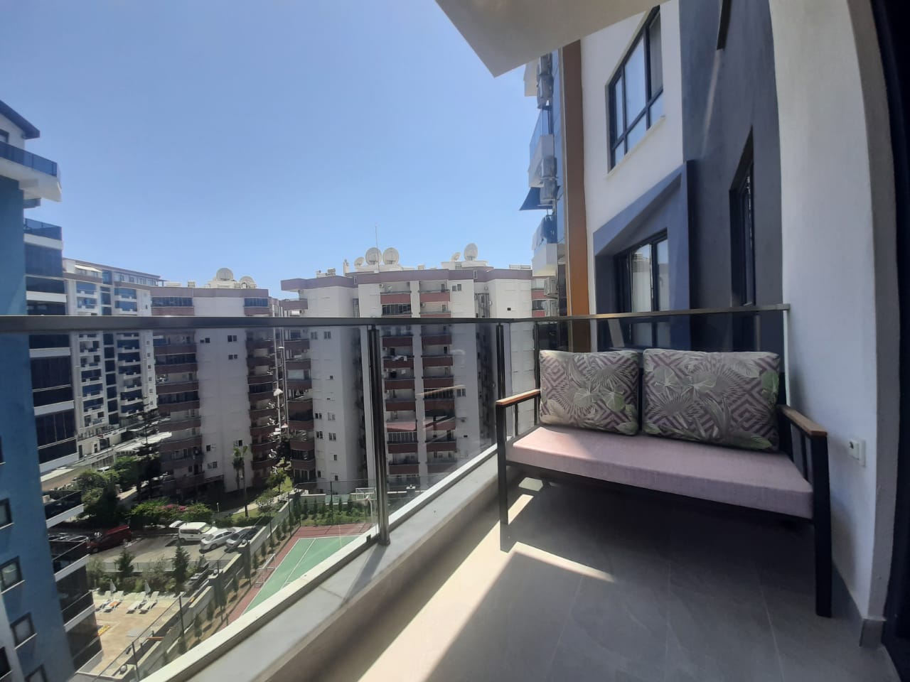 Cam balkon, kanepe ve geniş şehir manzarası Mahmutlar’daki daireden