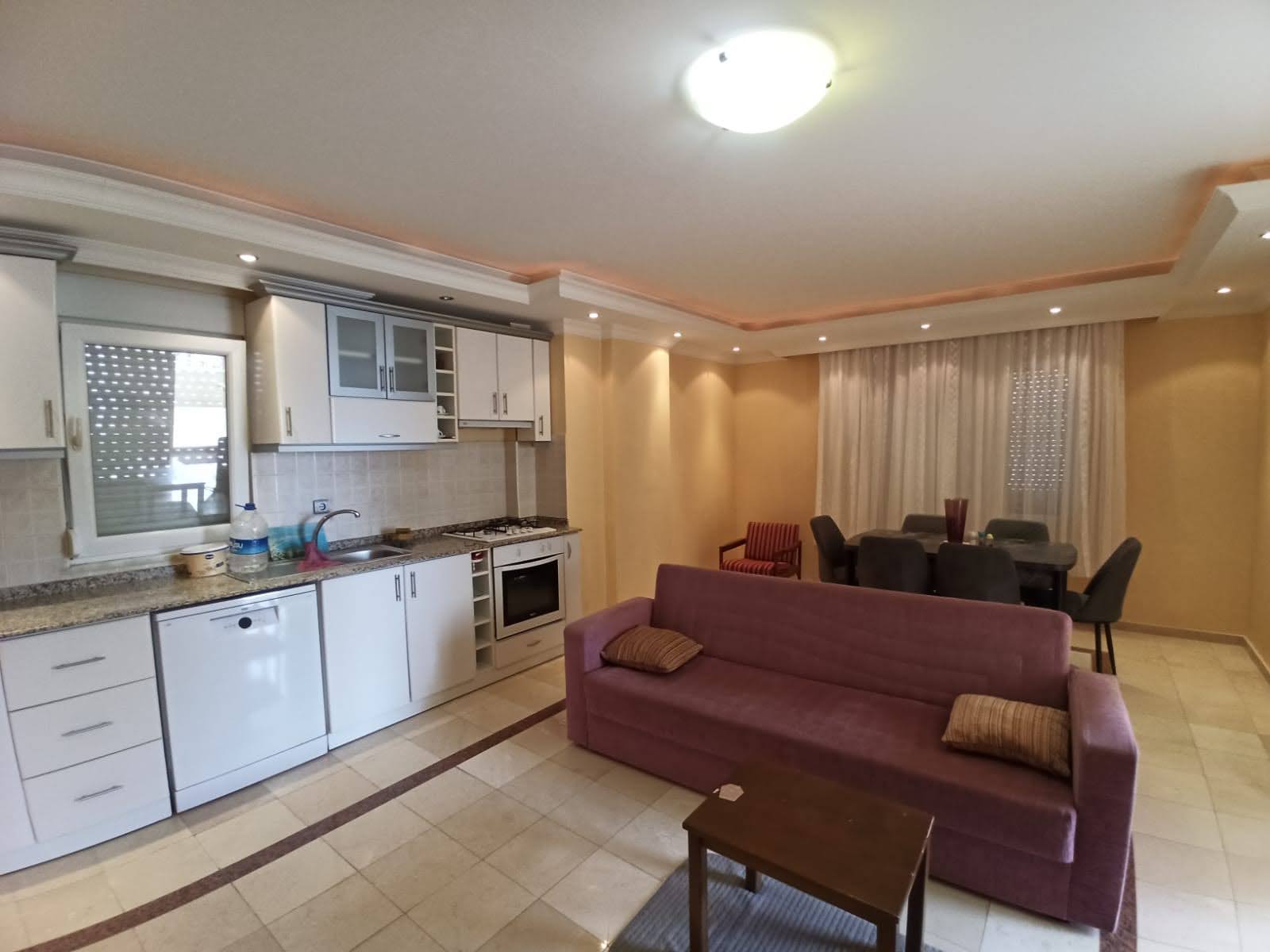 Tosmur’da 2+1 konutun mutfaklı salonunda yemek masası ve mor kanepe