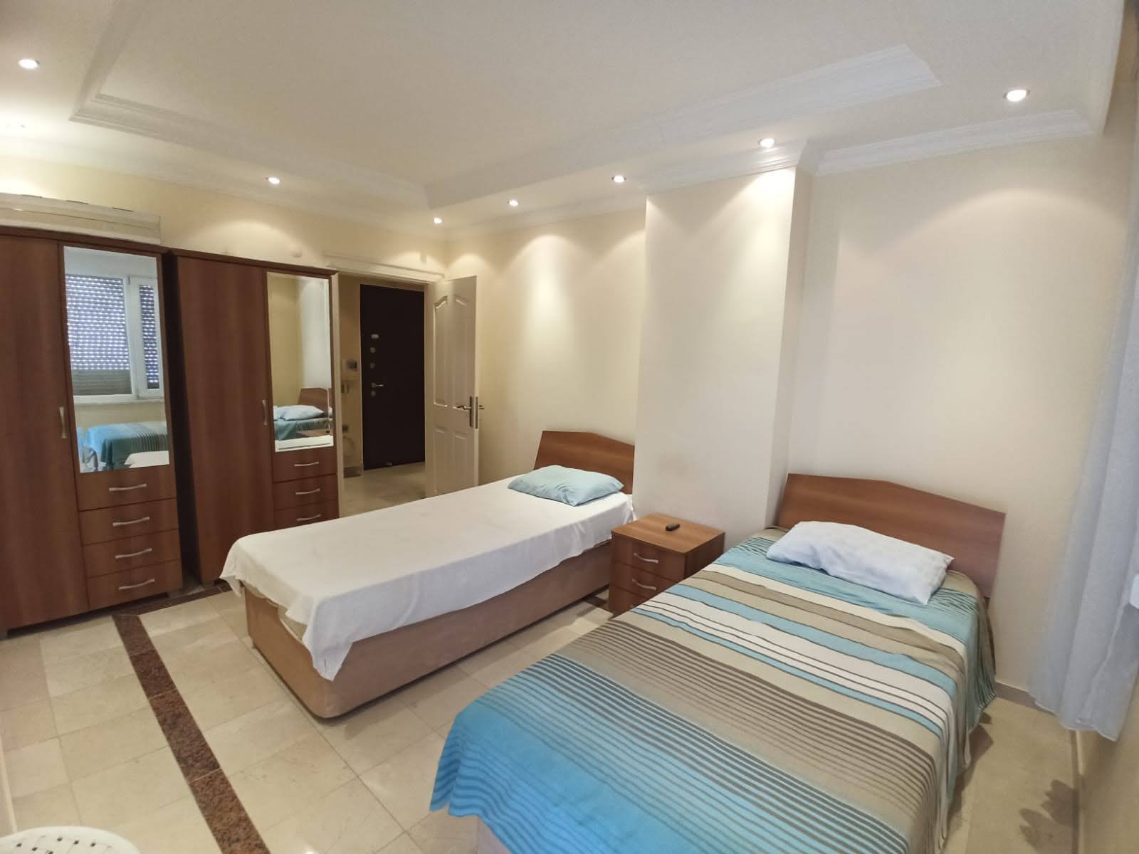 Alanya’da dairenin yatak odasında iki tek kişilik yatak ve aynalı ahşap dolap