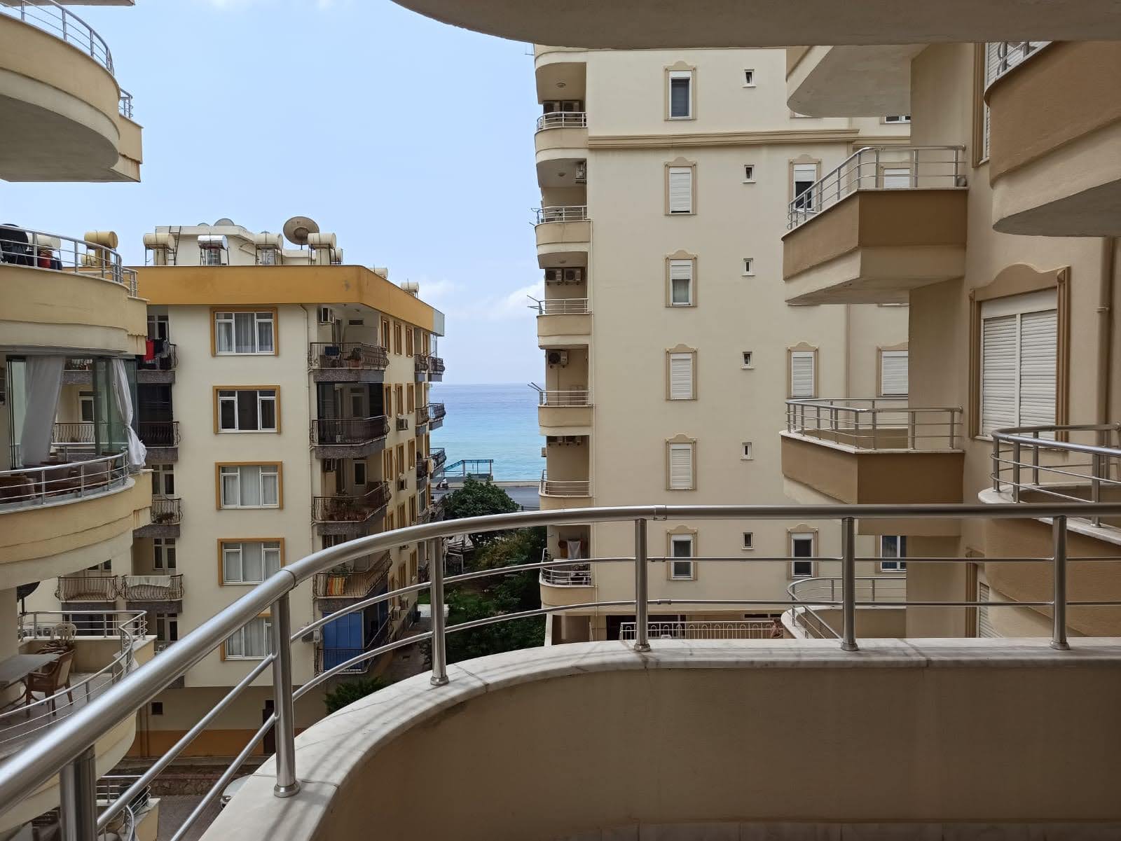 Tosmur’da satılık 2+1 dairenin kavisli balkonundan binalar arasındaki deniz açıklığı