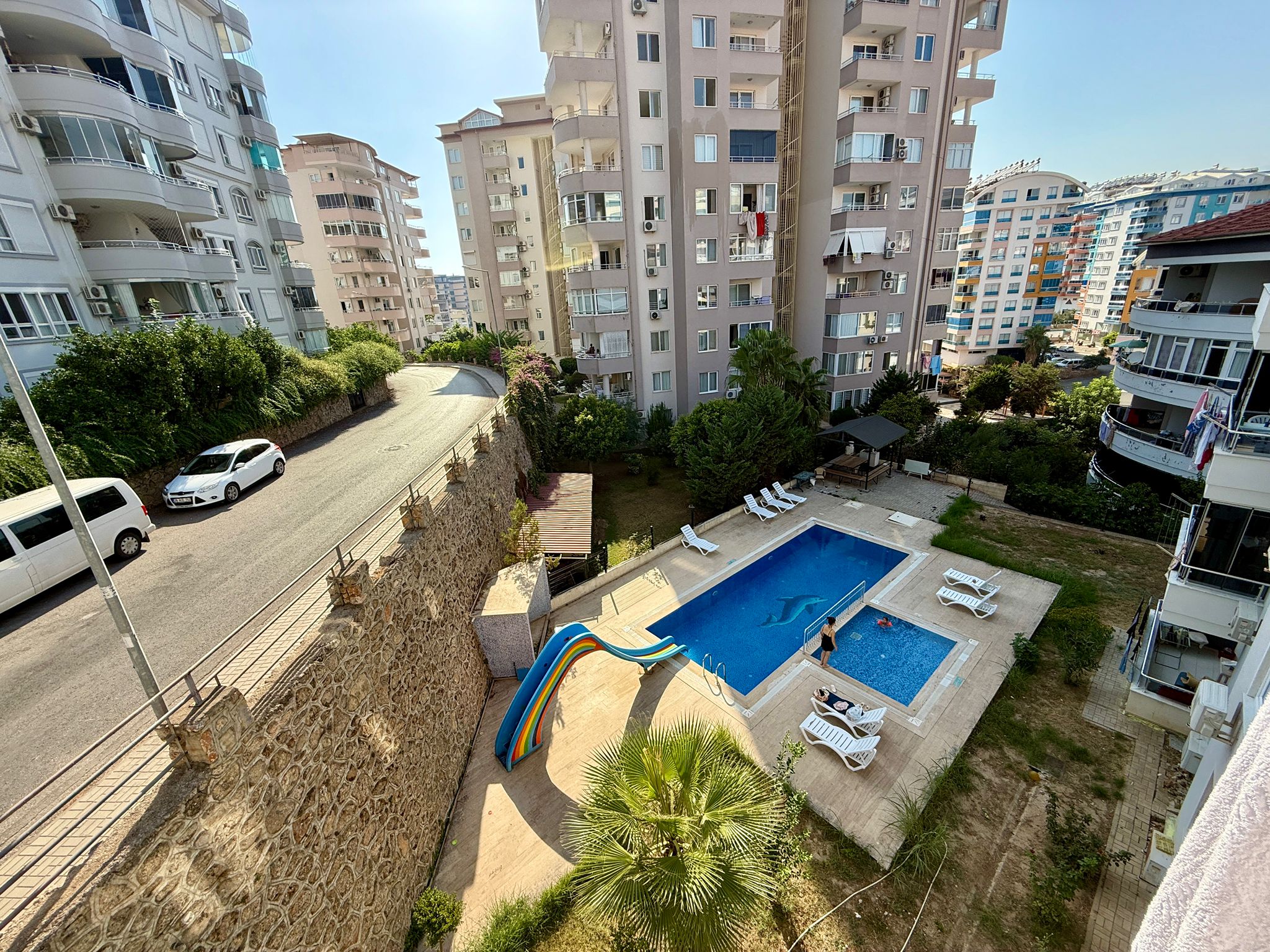 Alanya’daki rezidansın havuzunda renkli kaydırak, beyaz şezlonglar ve palmiye