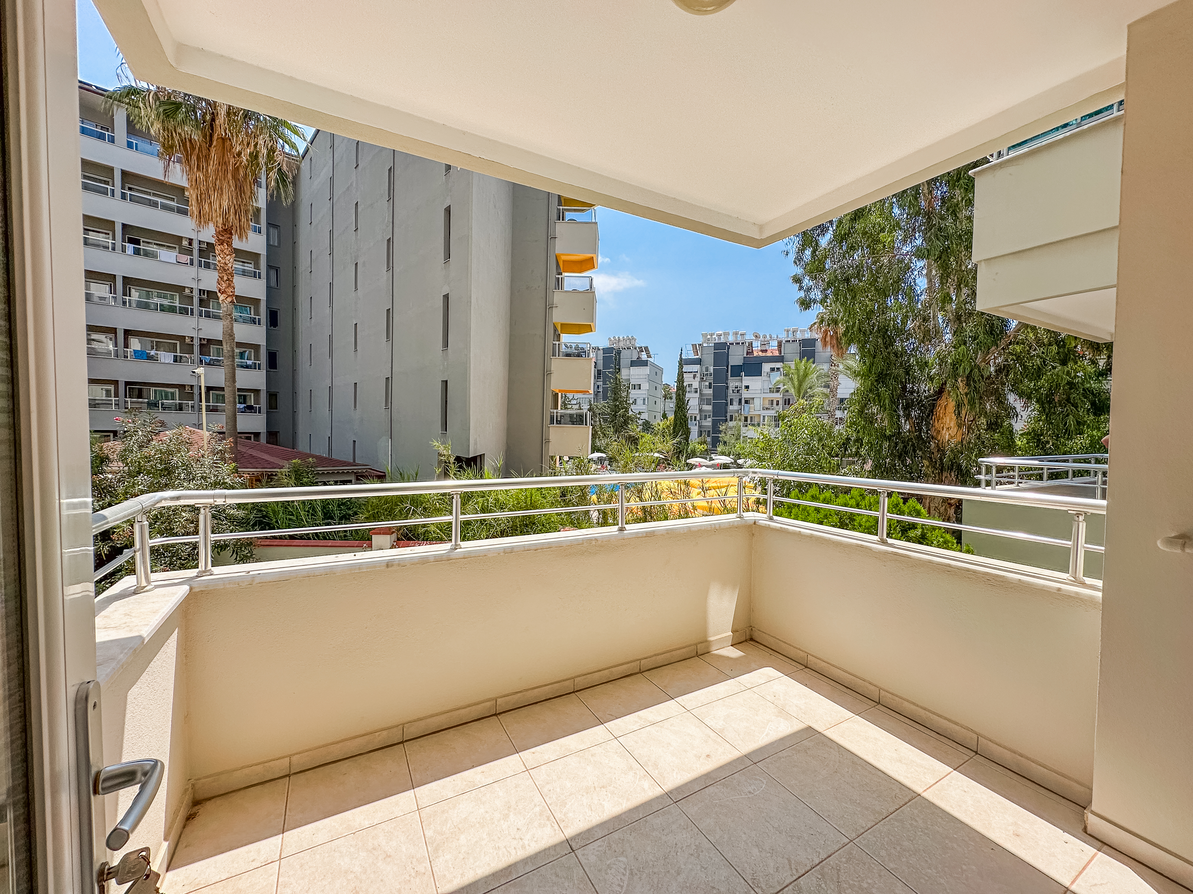 Tosmur’da satılık dairede açık kapılı köşe balkon, metal korkuluklar ve ağaçlar