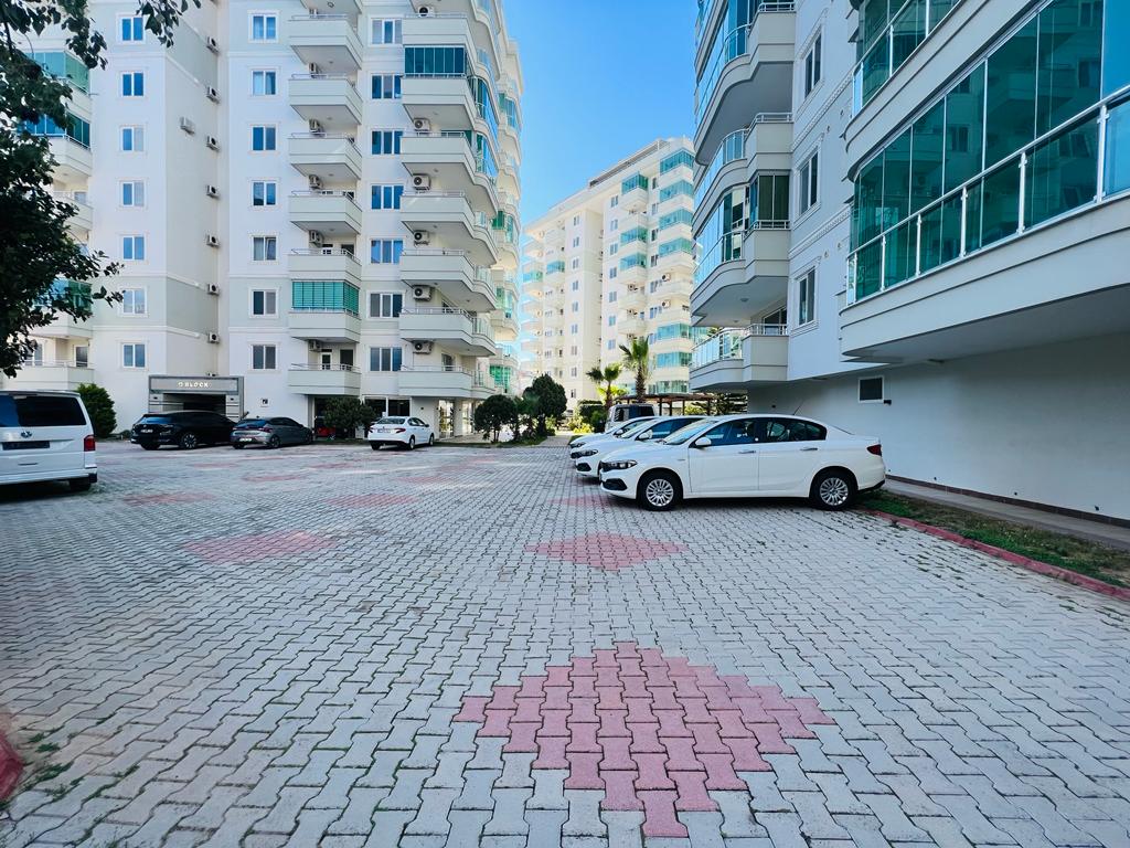 Tosmur’da geometrik desenli taş döşeme ve park edilmiş araçlarla açık otopark
