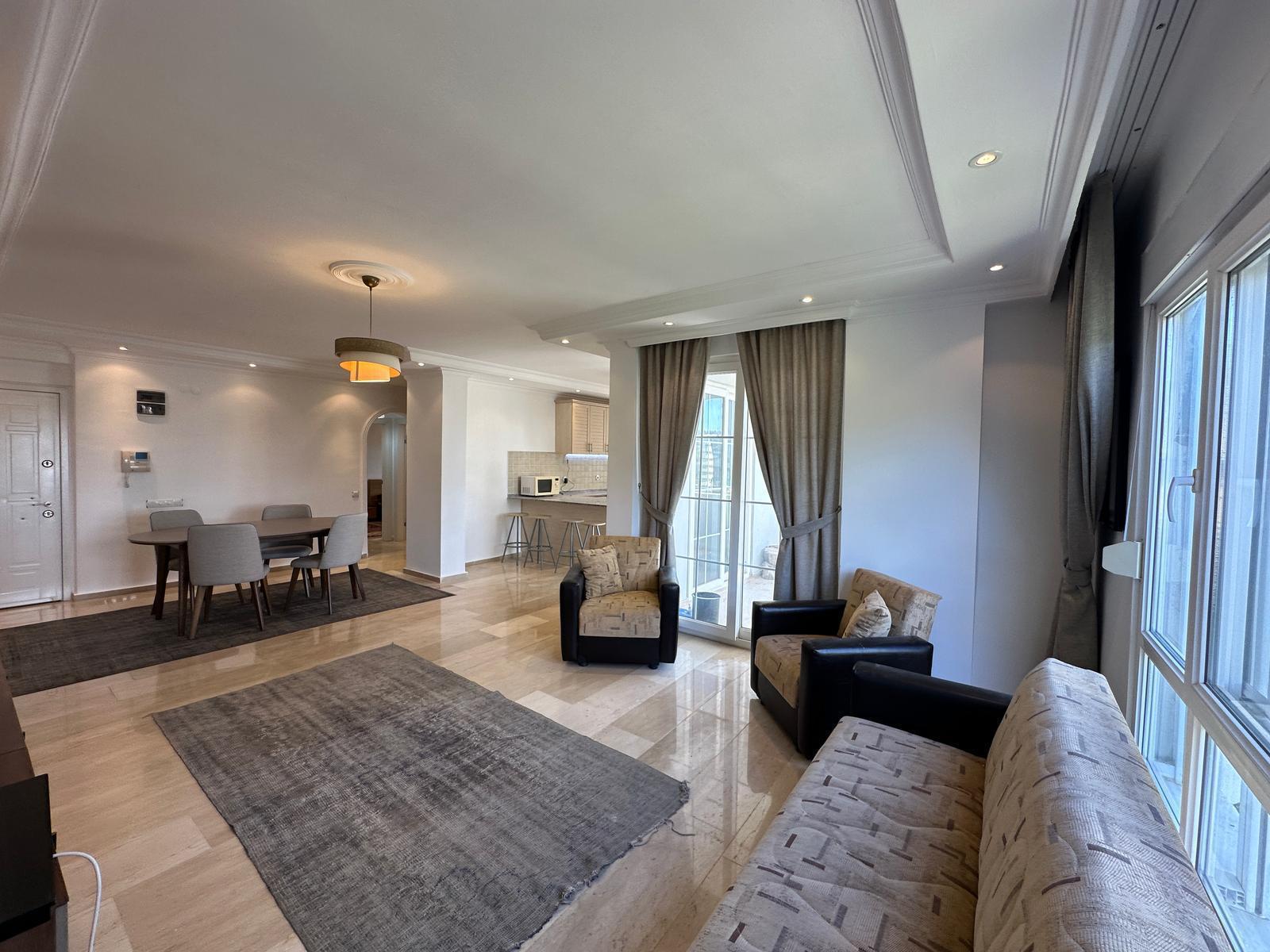 Beyaz mutfak, bar tezgâhı ve dört kişilik oval masalı mutfaklı salon, 2+1 dairede