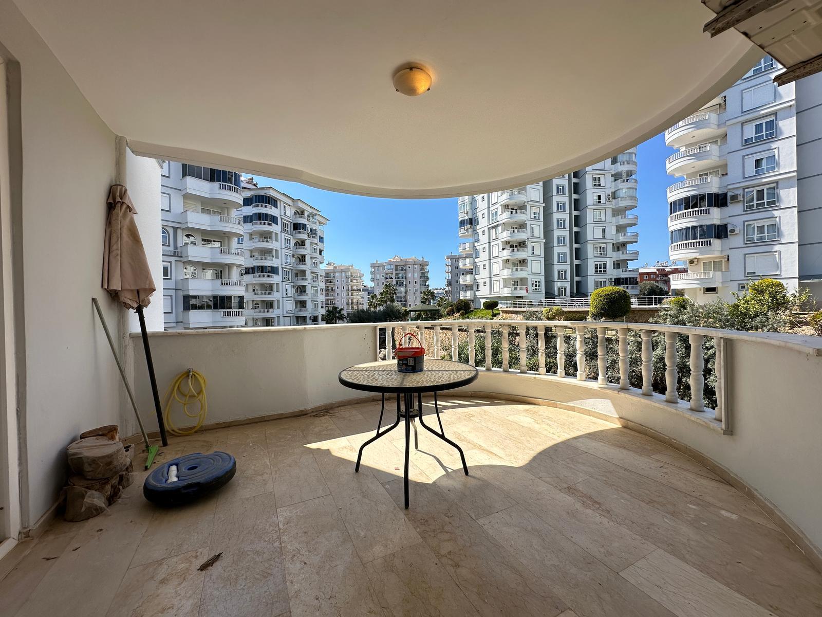 Yarı dairesel kapalı balkon, yuvarlak masa ve beyaz korkuluklar, Türkiye’deki konutta