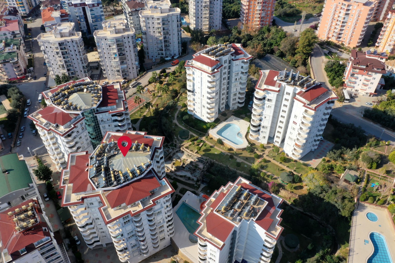 Çim ve palmiyeler arasındaki kıvrımlı havuz, denize yakın konutların bulunduğu sitenin avlusunda