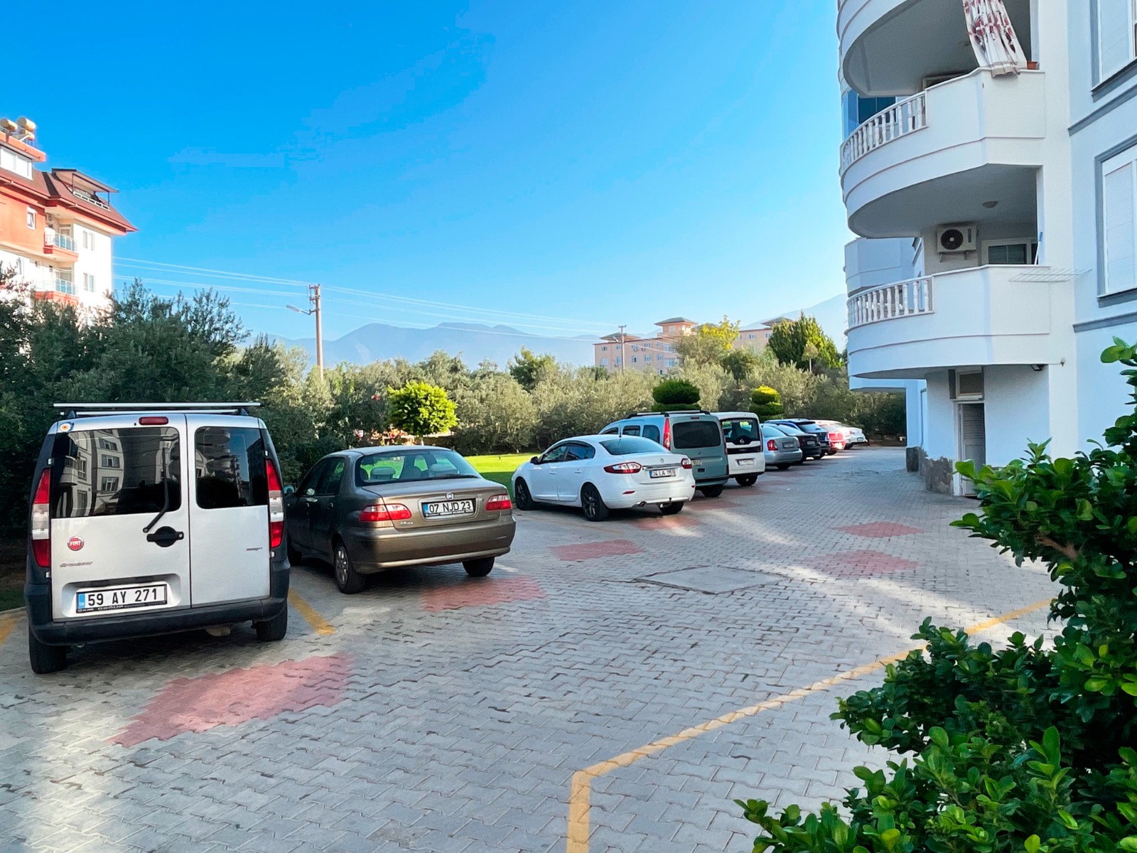 Sarı çizgili açık otopark ve araç sırası, Tosmur’daki konutların yer aldığı binanın yanında