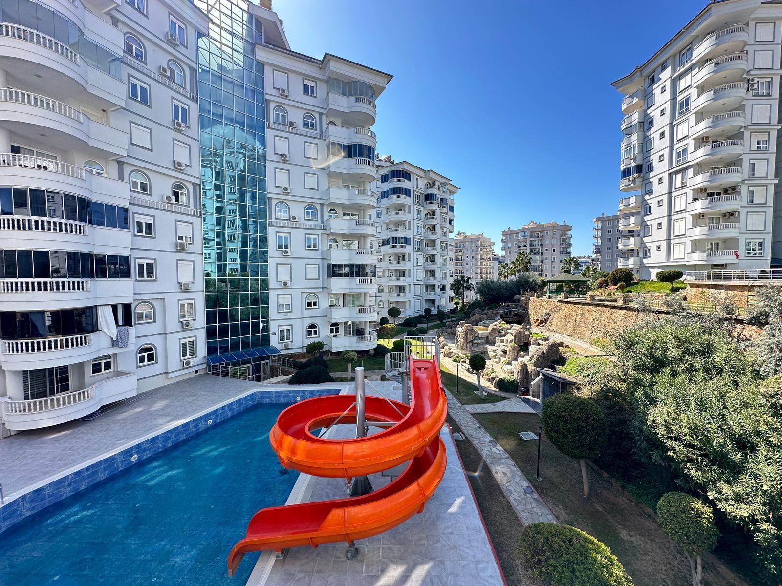 Turuncu spiral kaydıraklı açık havuz, Türkiye’de apartman sakinleri için düzenlenmiş avluda