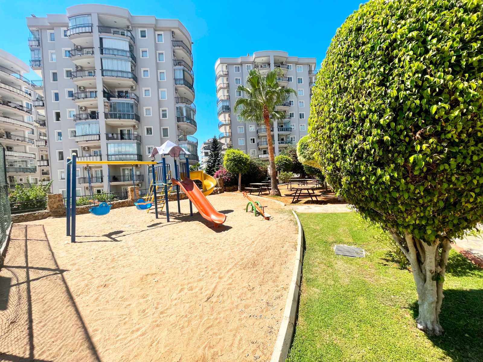 Turuncu kaydırak, iki salıncak ve kum zeminli çocuk alanı, daire sakinleri için