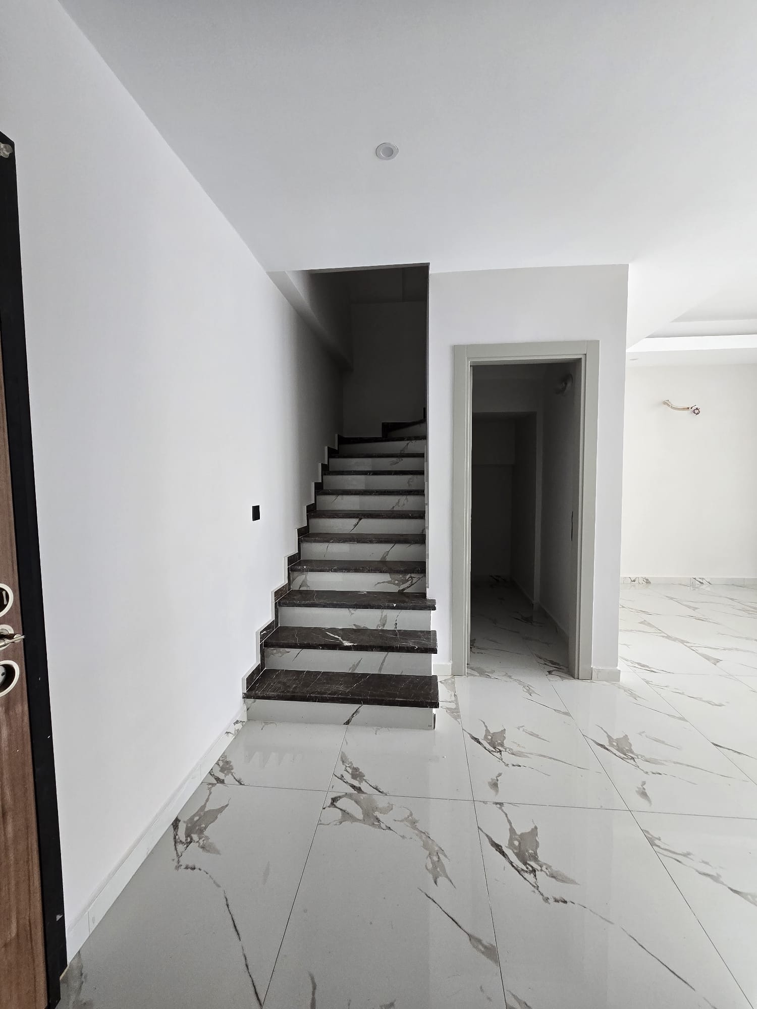 Koyu basamaklı iç merdiven, beyaz rıhtlar ve yanındaki koridor Tosmur’da