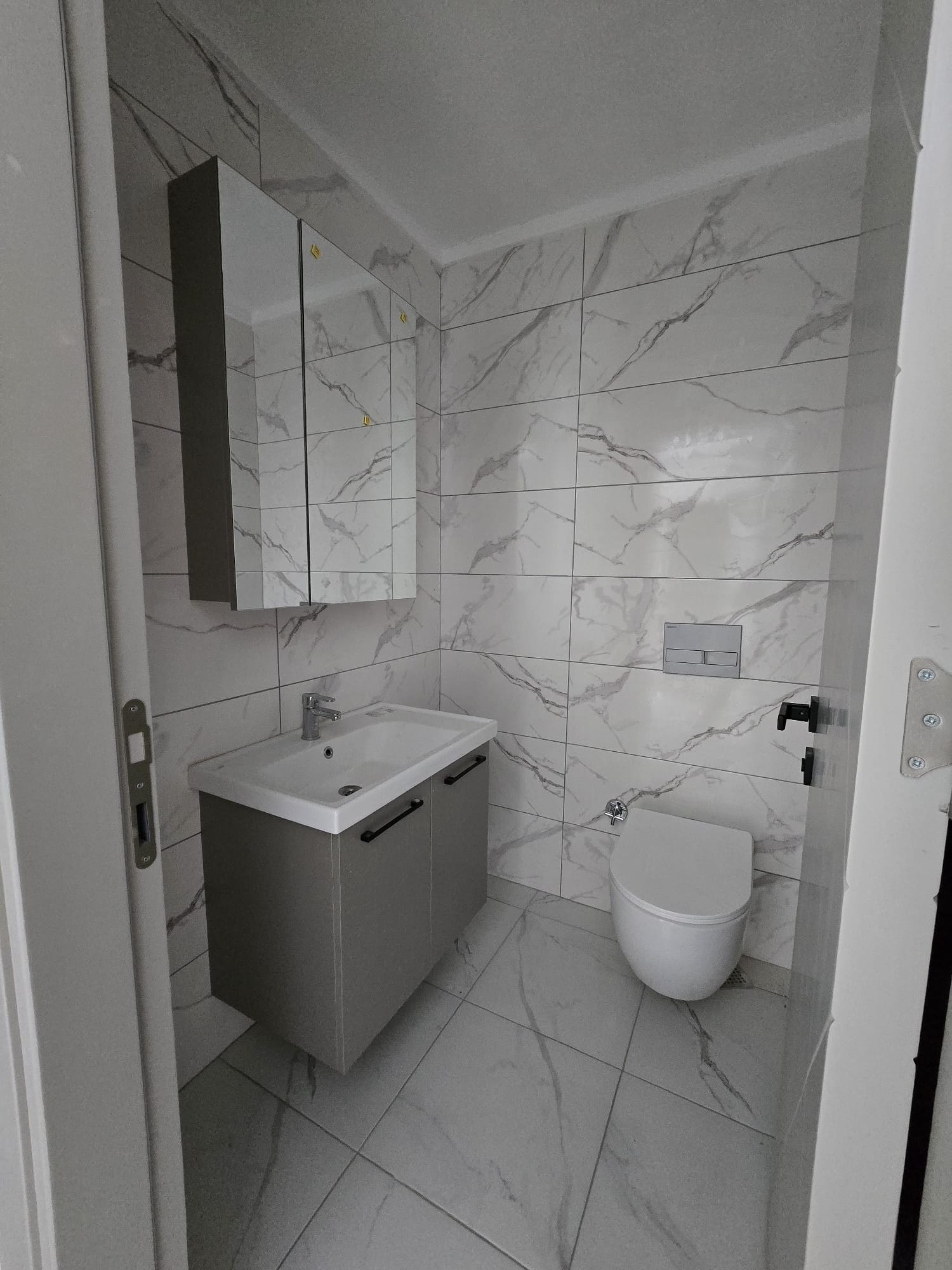 Mermer desenli banyoda asma klozet, gri dolaplı lavabo ve duvar tipi aynalı dolap Tosmur’da