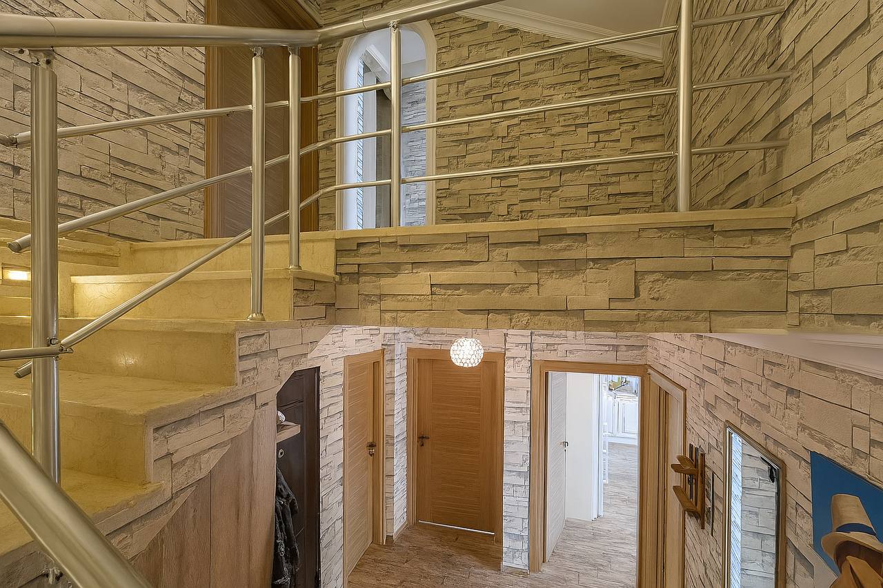 Stone-lined staircase with an arched window in a top-floor apartment in Tosmur