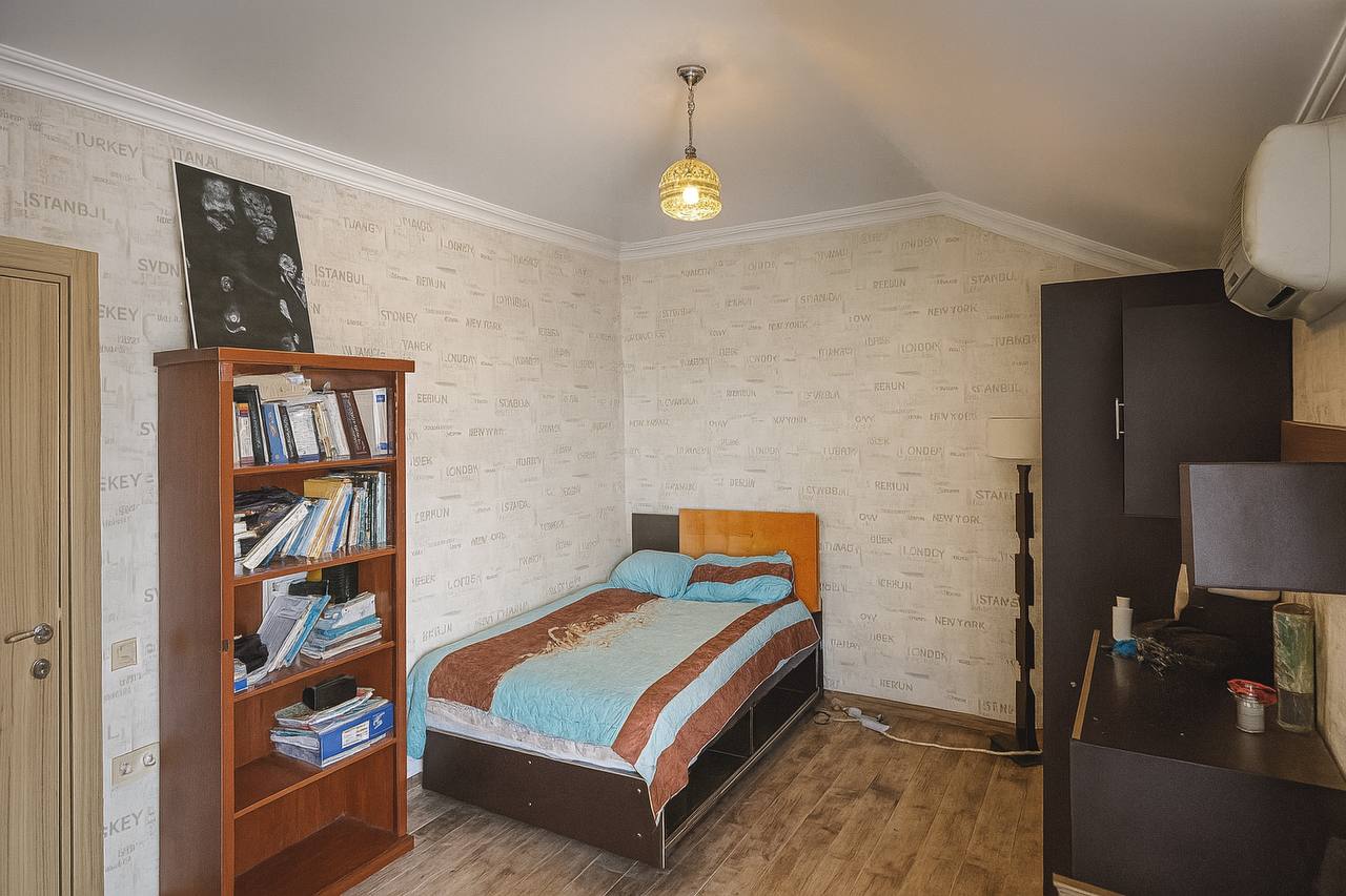 Bedroom with a bed, bookcase and dark open shelving in a duplex