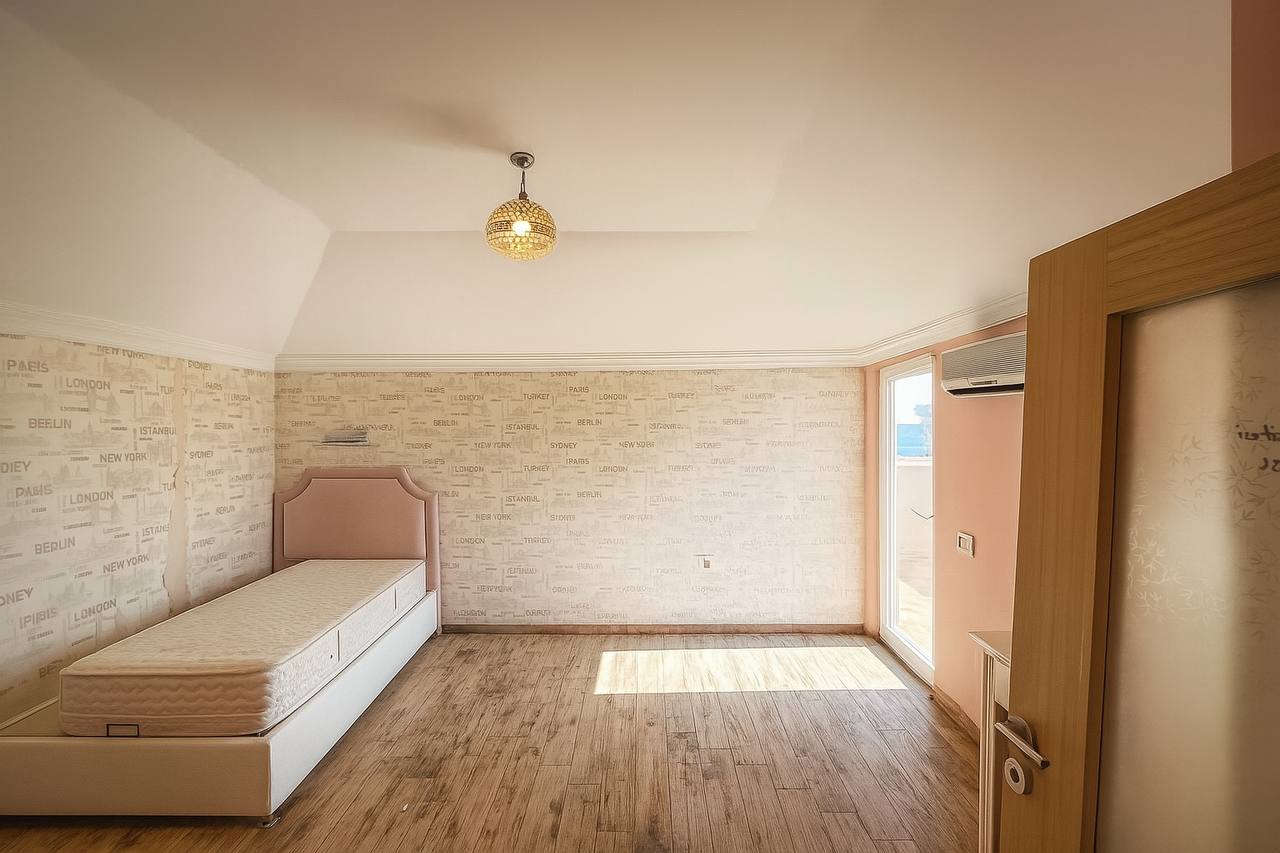 Bedroom with a single bed with drawers and a panoramic window in a penthouse in Tosmur
