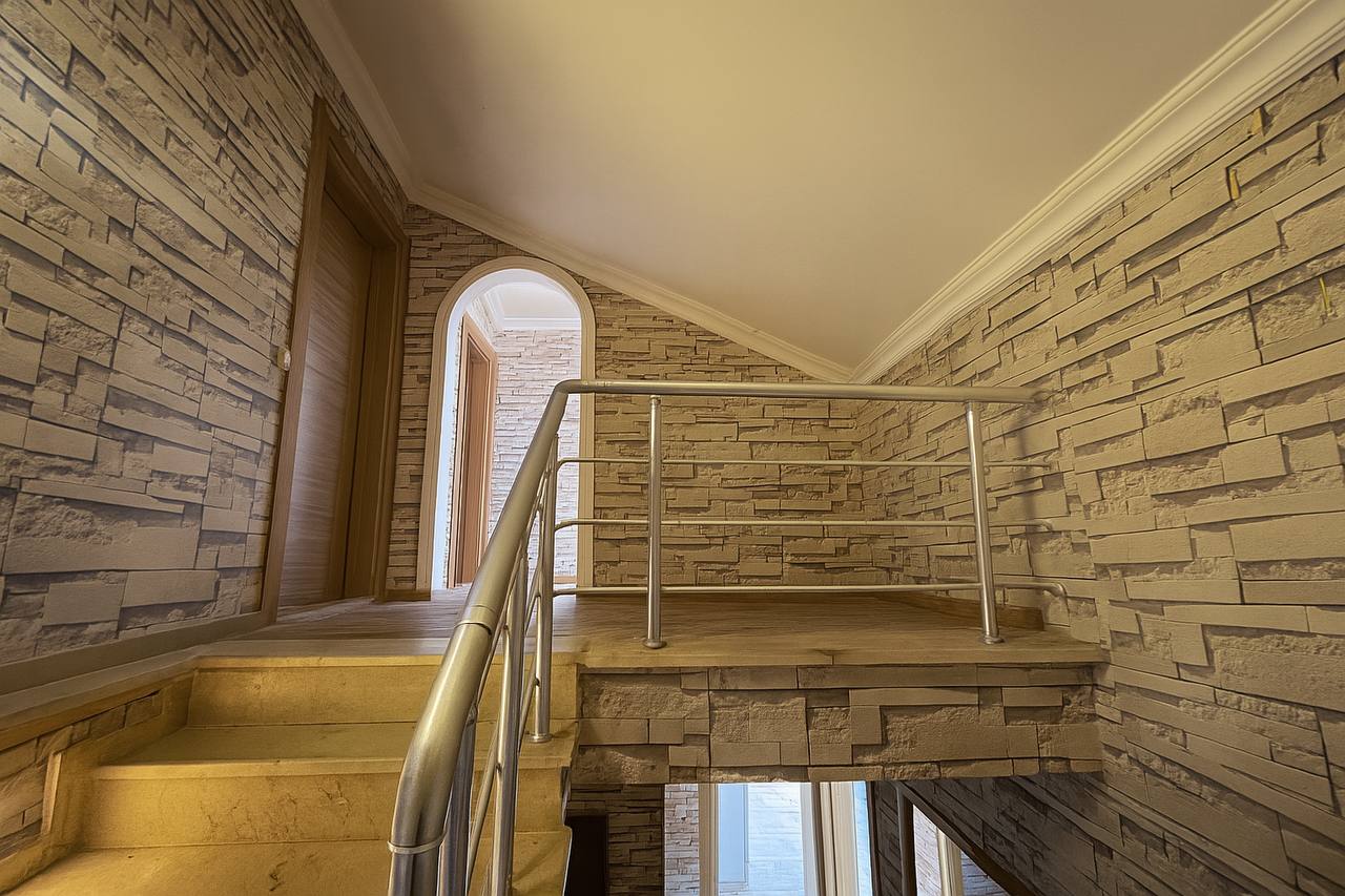 Interior staircase with stone steps and a wooden door in a top-floor apartment in Tosmur